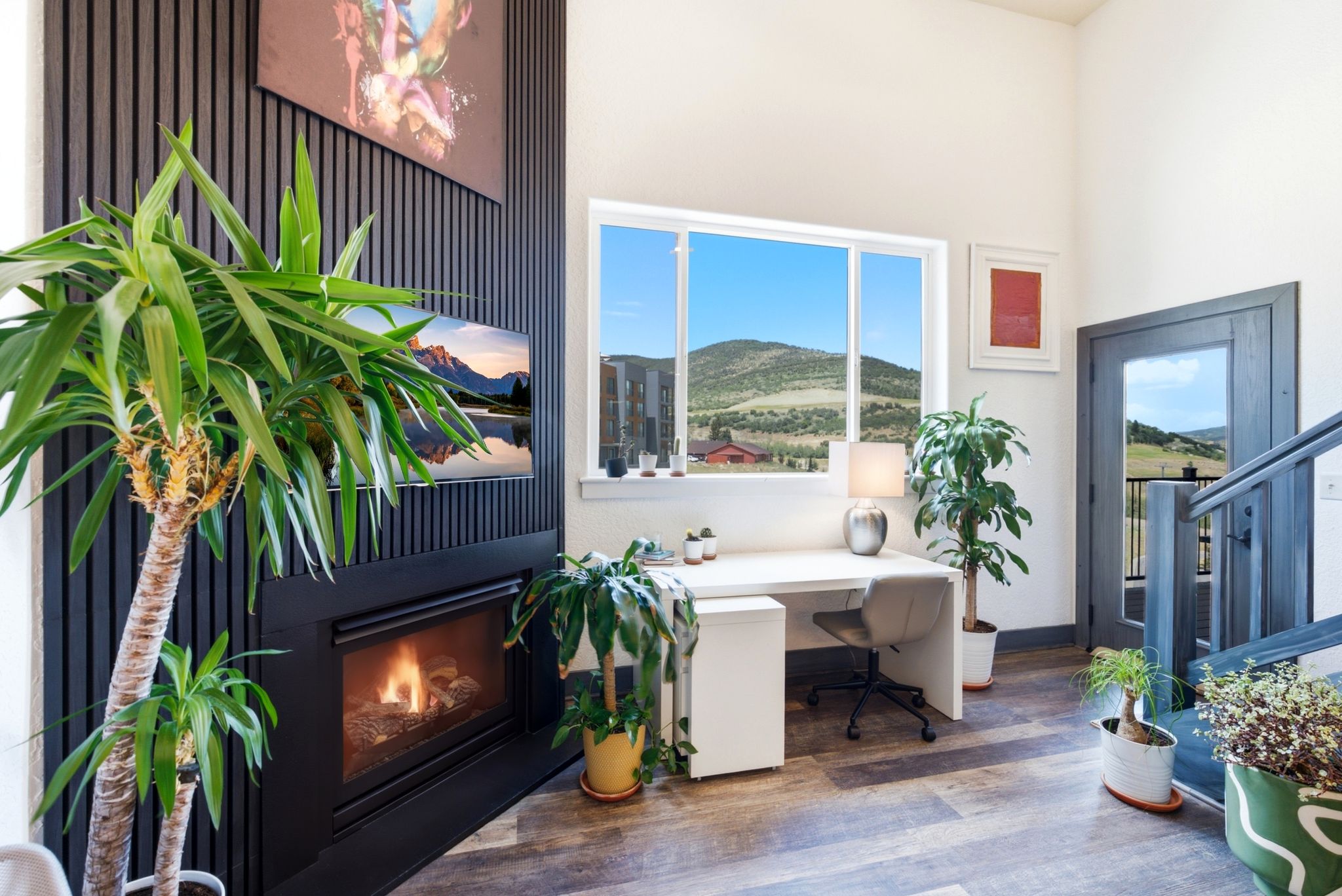 Spacious interior featuring a contemporary fireplace with a black slatted accent wall, high ceilings, a large window, and wood-finish flooring