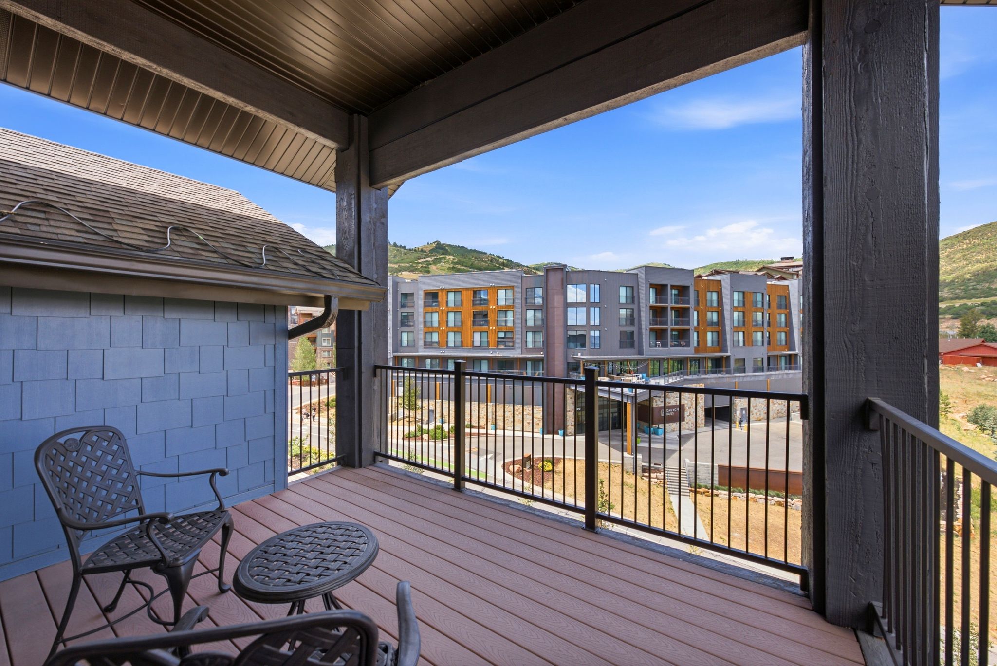Outdoor balcony featuring composite decking, black metal railings, and a wood-finish ceiling
