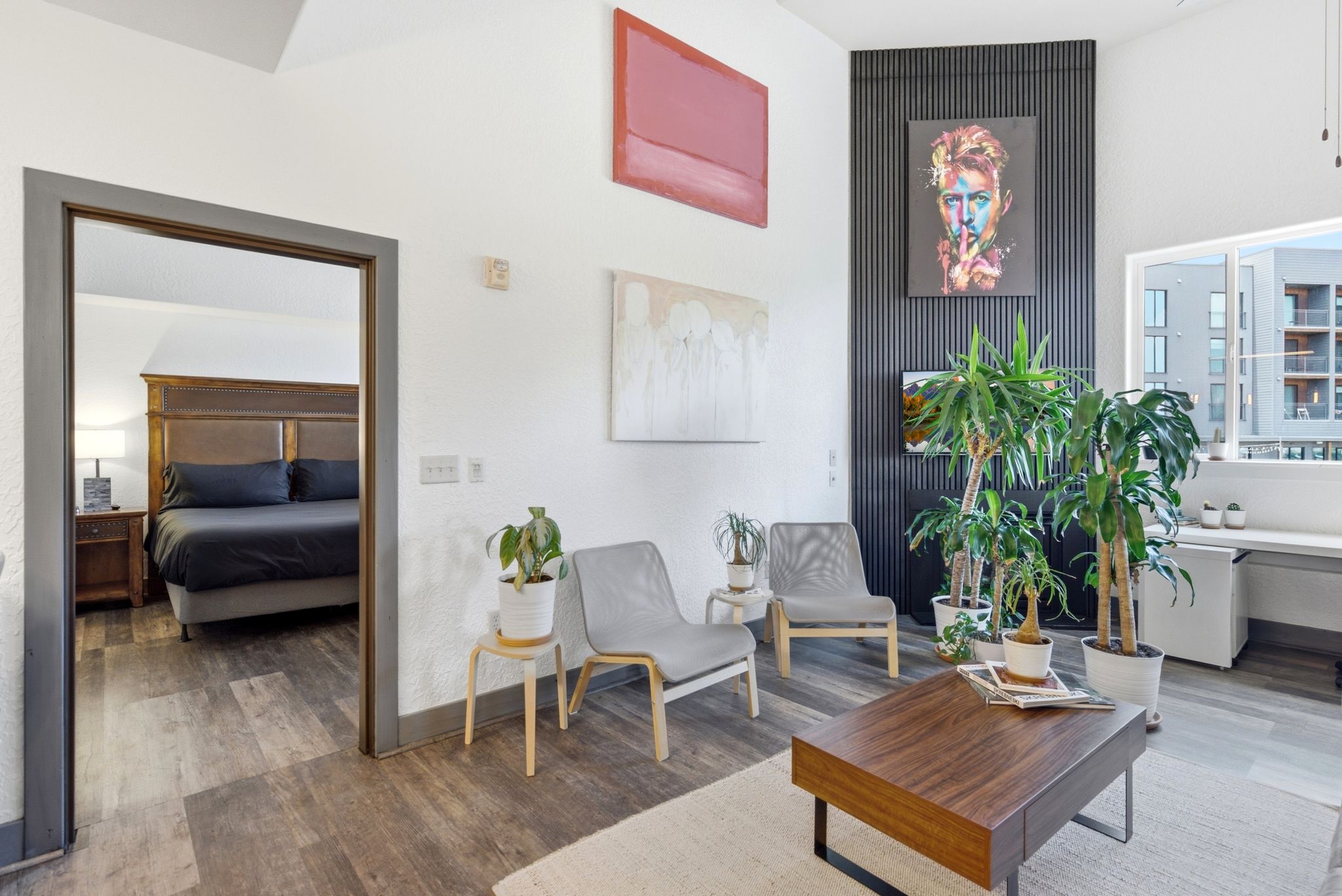 Spacious interior featuring wood-finish flooring, a contemporary accent wall, high ceilings, and an integrated desk area below a large window