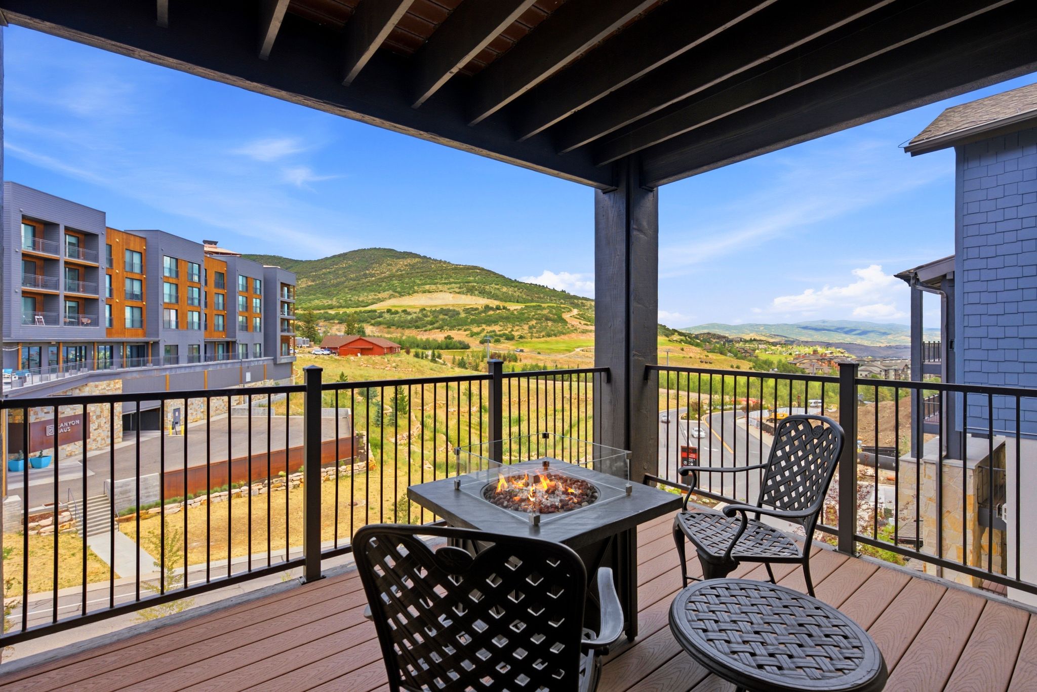 Covered balcony featuring wood-finish flooring, black wrought iron railings, and a built-in fire pit