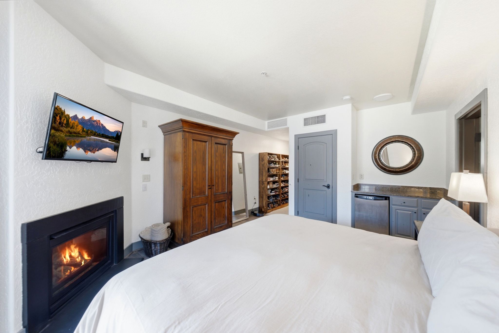 Bedroom featuring a built-in fireplace, wall-mounted television, and a custom built-in bar area with a compact refrigerator