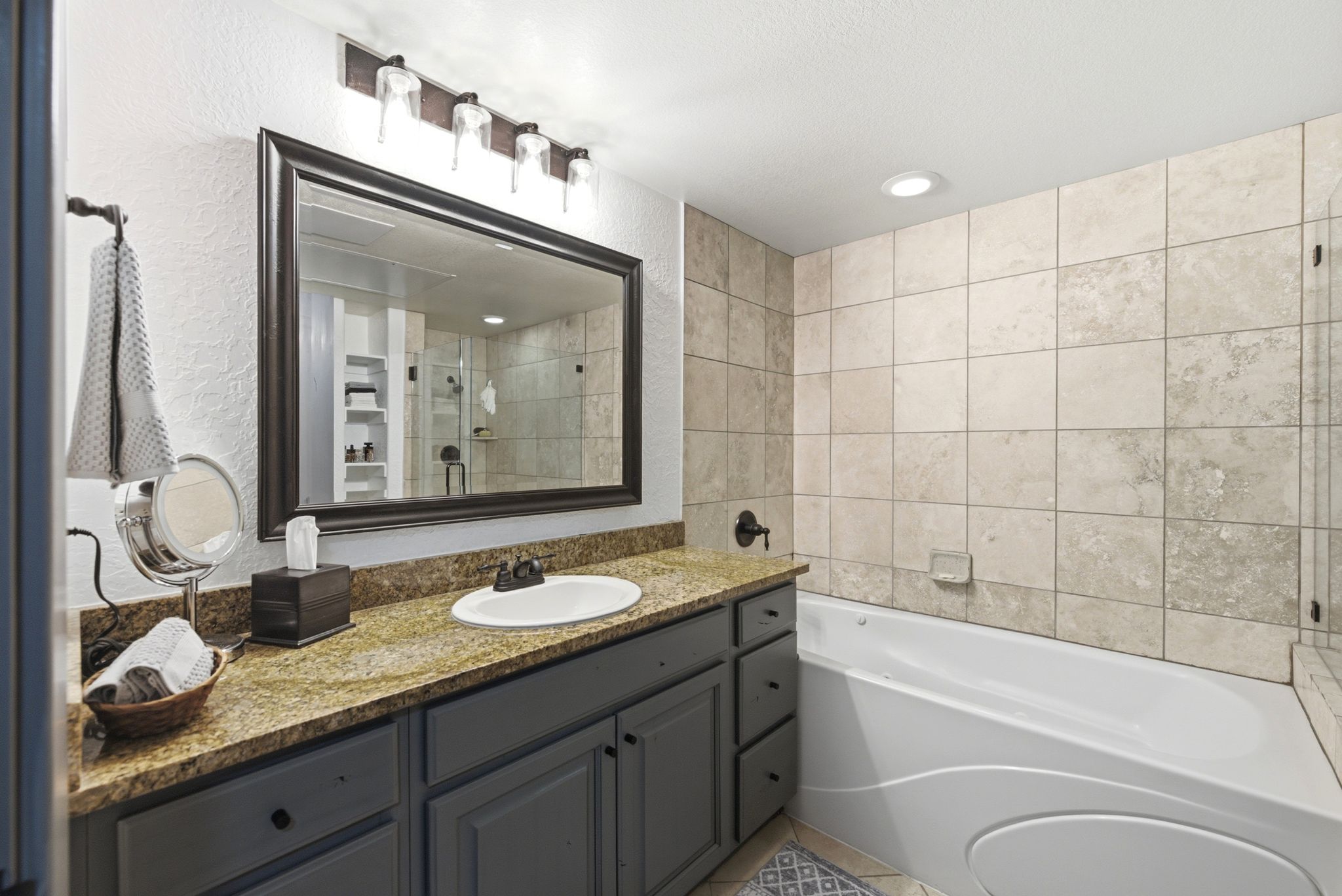 Bathroom featuring a vanity with granite countertop, undermount sink, and dark cabinetry