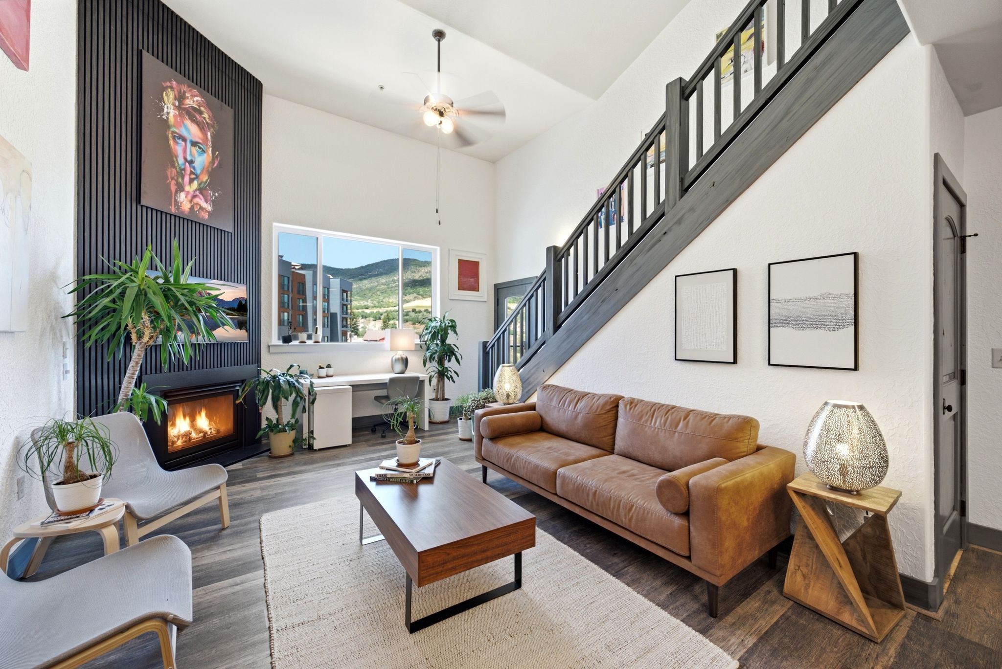 Living space featuring a striking black accent wall with a built-in fireplace, high vaulted ceilings, and wood-finish flooring