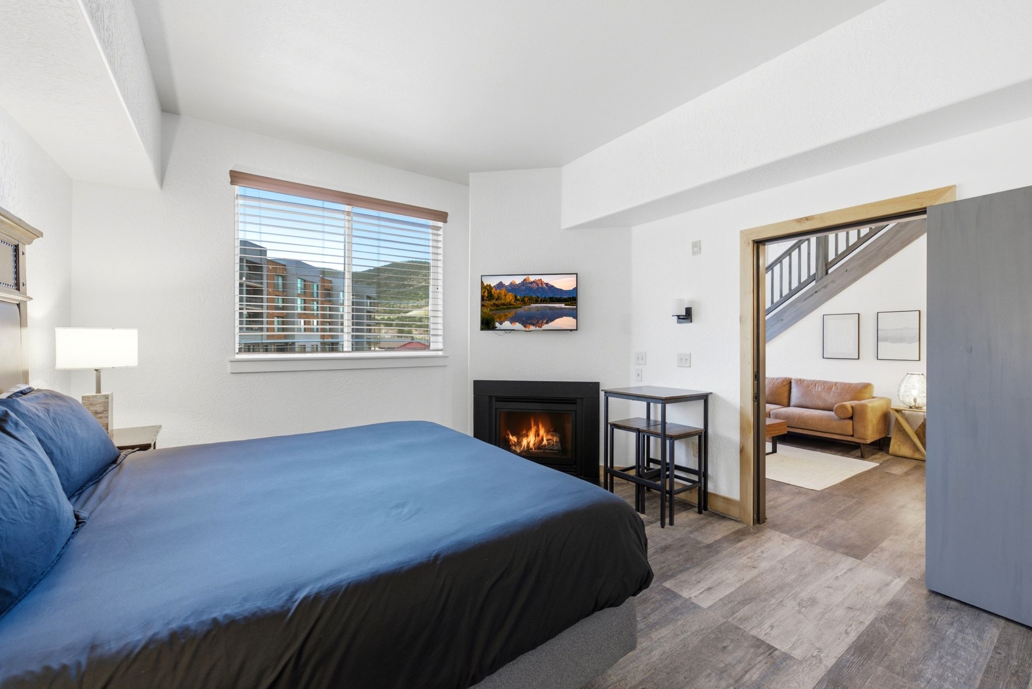 Bright sleeping area featuring a built-in fireplace, a window with blinds, and wood-finish flooring