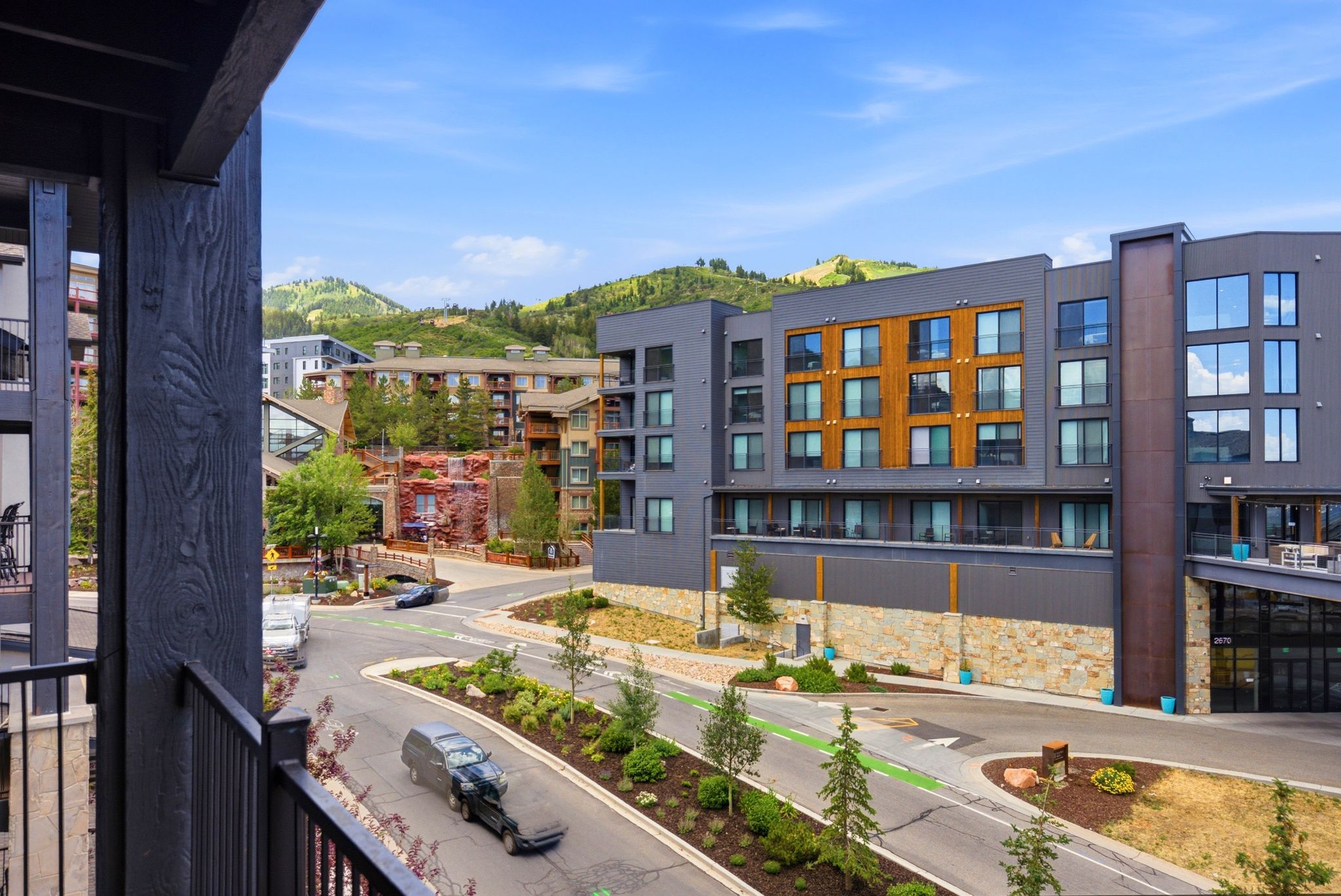 Modern building exterior with a mountain backdrop, featuring a mix of dark paneling and wood-finish accents