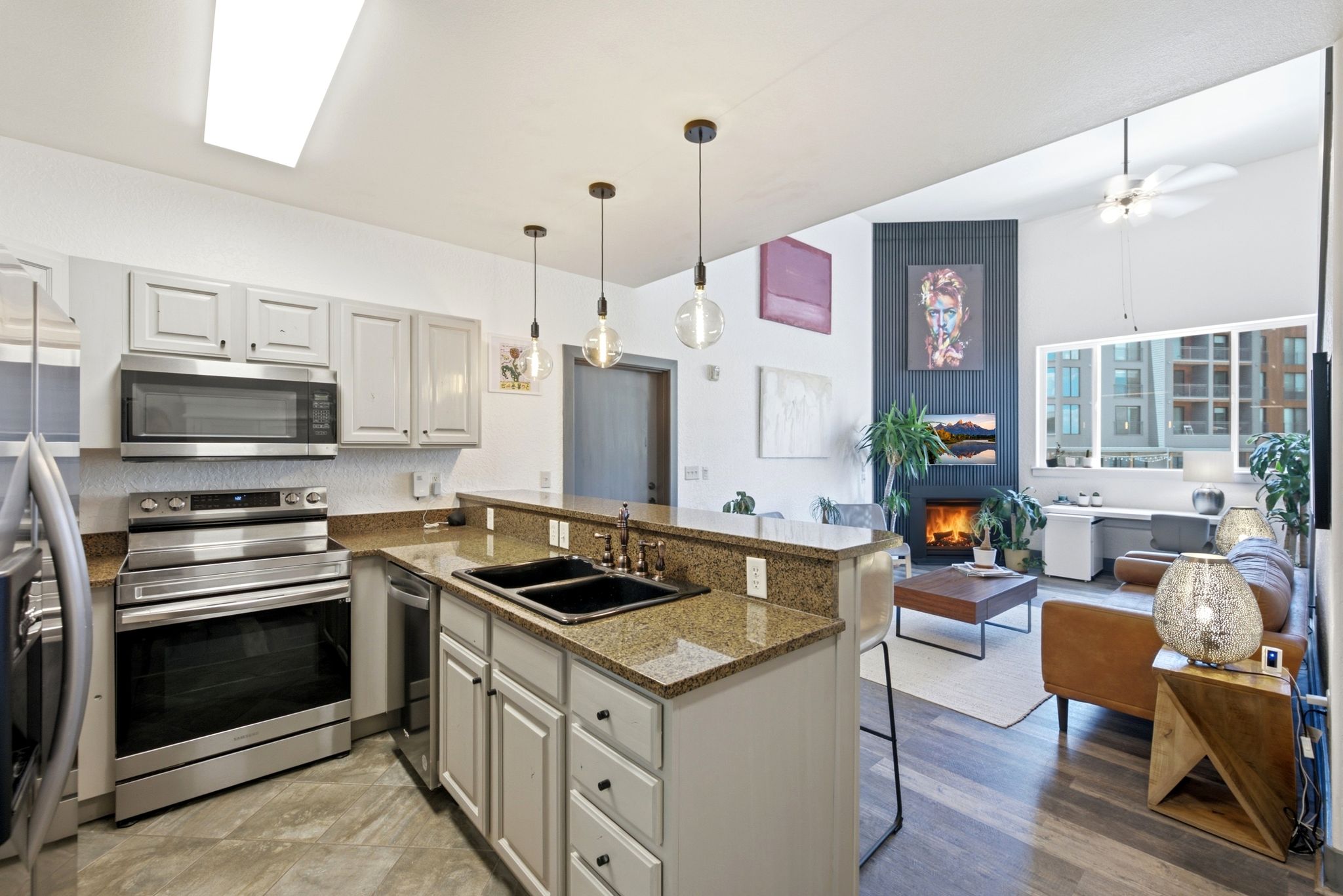 Open-concept kitchen featuring granite countertops, stainless steel appliances, a double basin sink, and pendant lighting