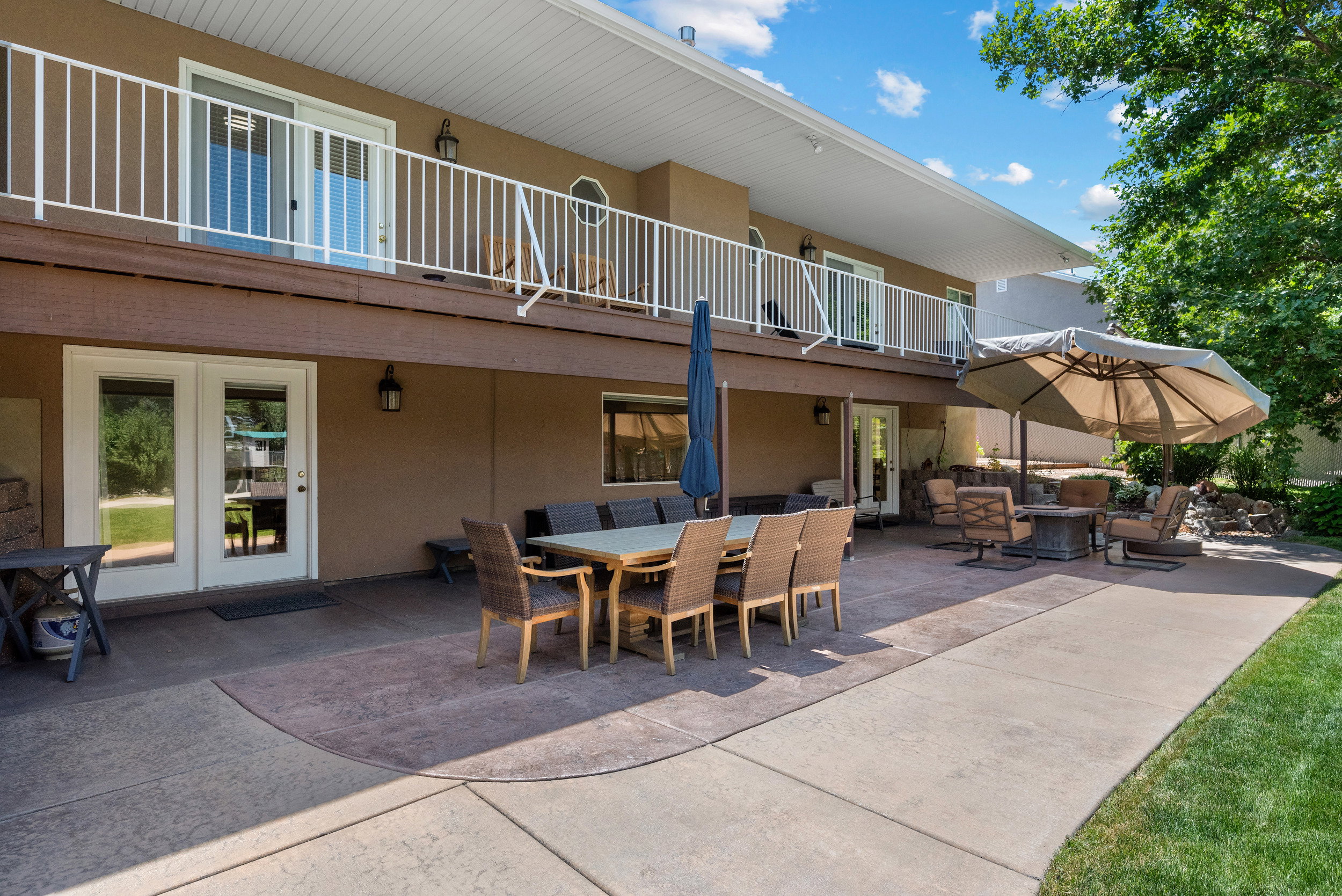 Expansive concrete patio with seating area and entrance to basement level