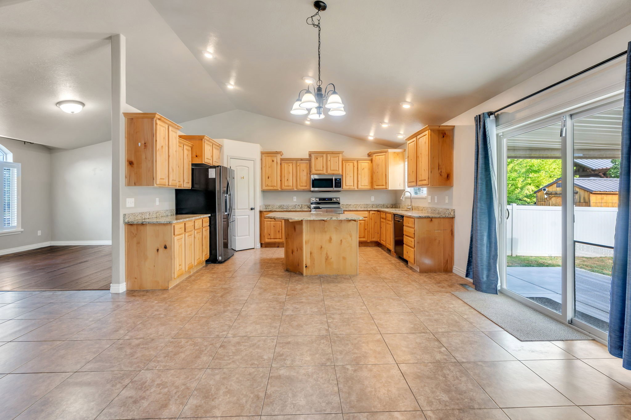 Kitchen featuring wood cabinetry, light-toned countertops, a central island, stainless steel appliances, and tile flooring
