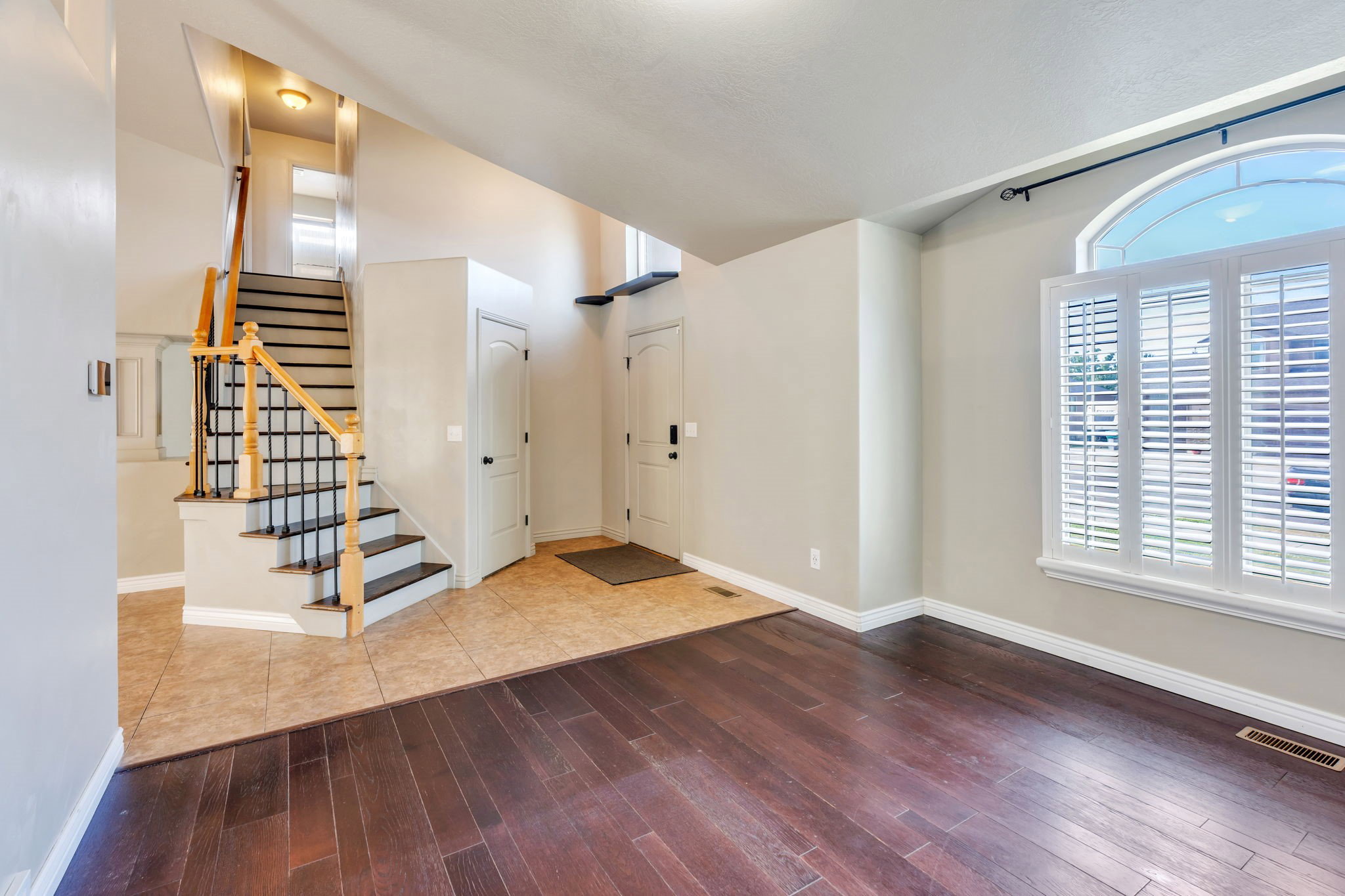 Foyer featuring a grand staircase with wood newel posts, wrought iron balusters, and dark-stained treads