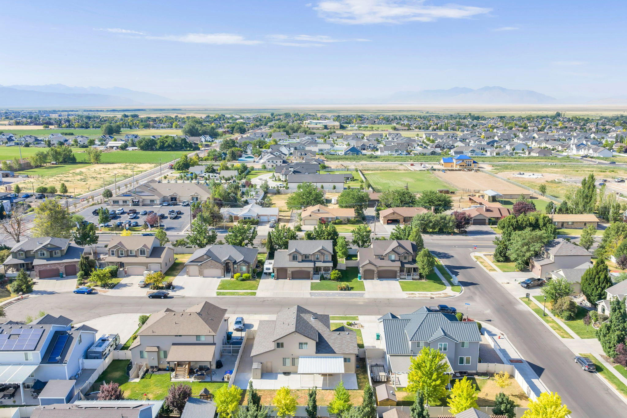 Aerial perspective showcasing a residential neighborhood with diverse housing styles, green spaces, and distant mountain ranges