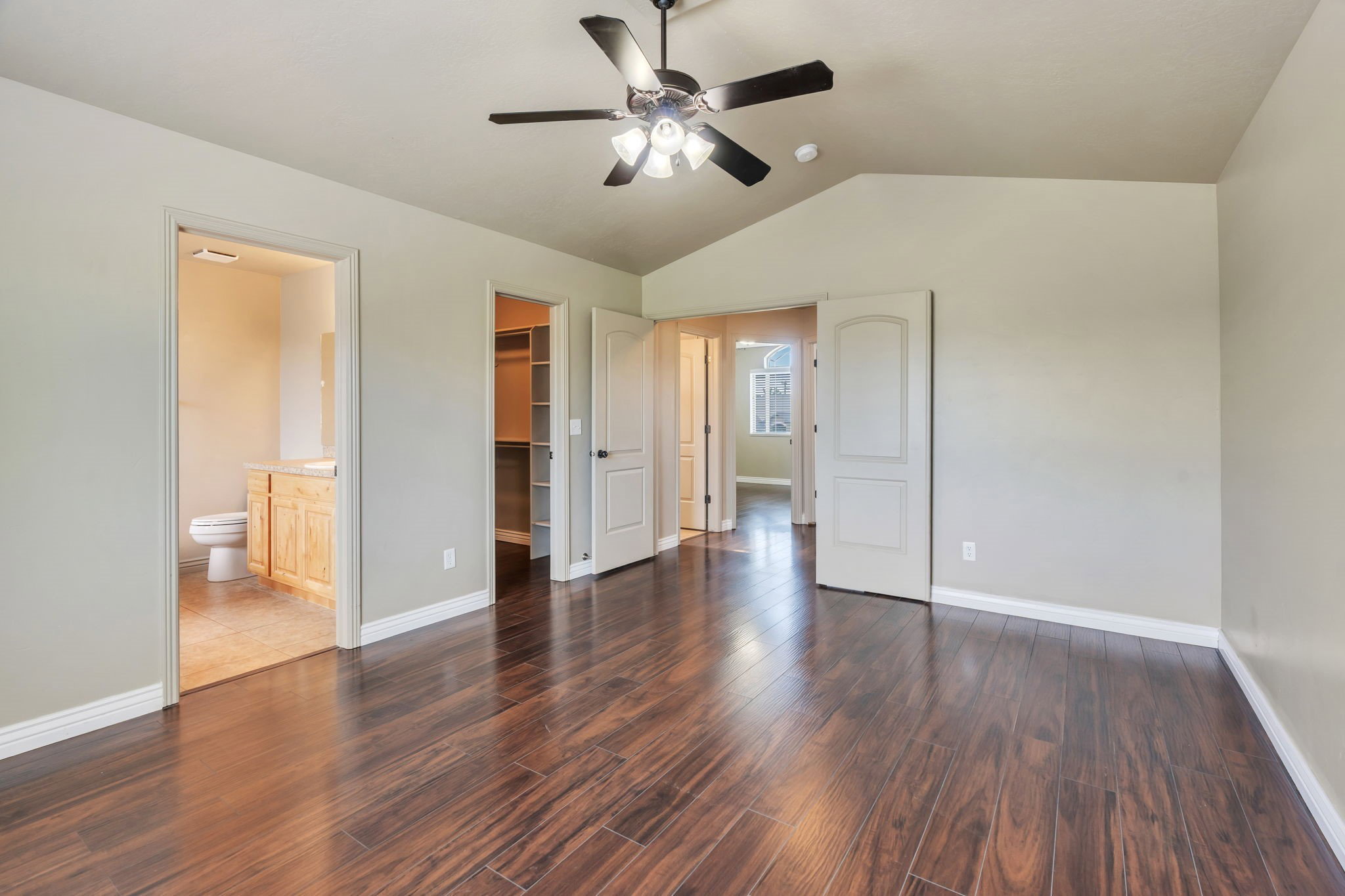 Spacious room featuring wood-finish flooring and a vaulted ceiling