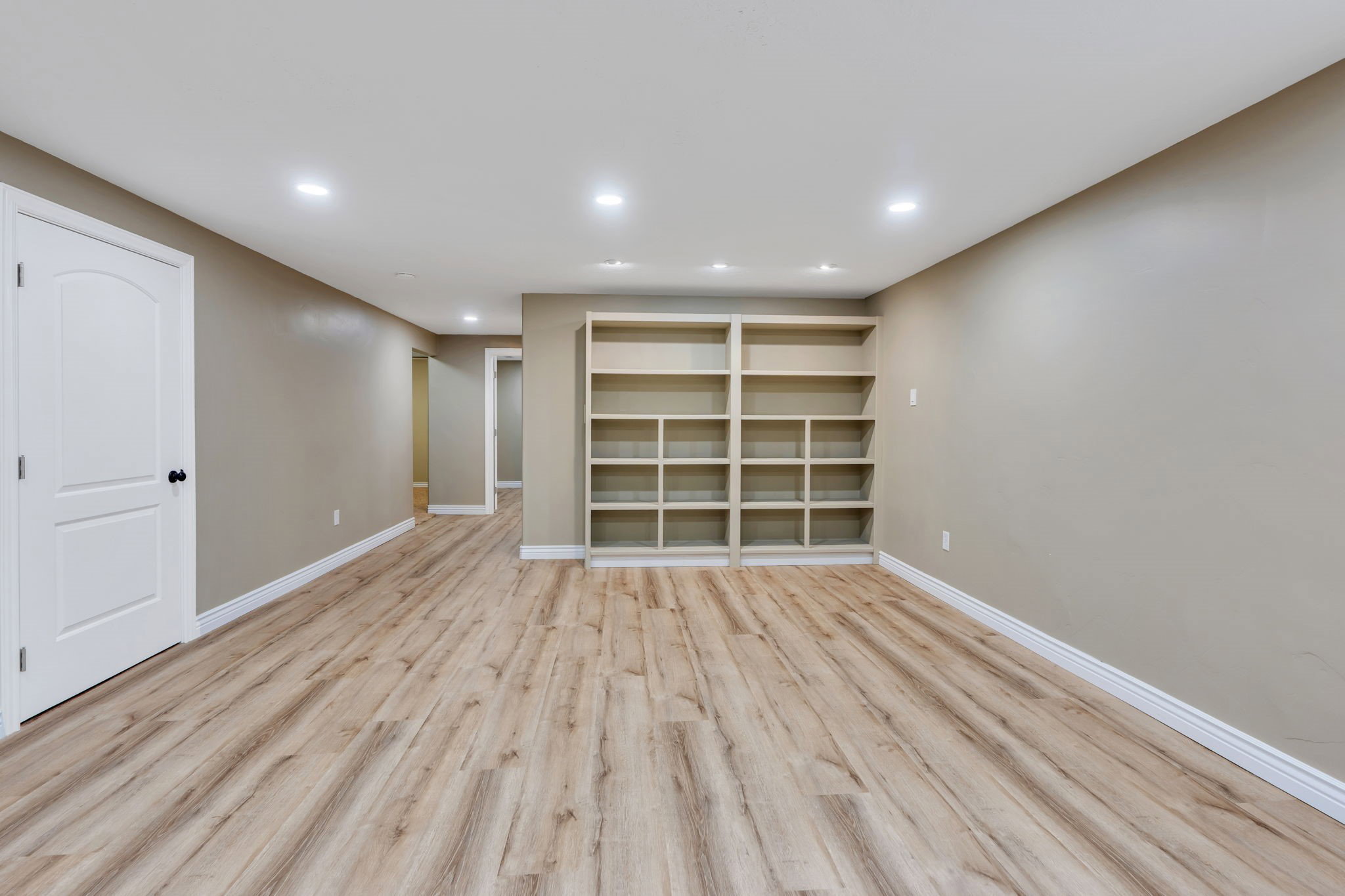Spacious room featuring wood-finish flooring, recessed lighting, and a built-in shelving unit