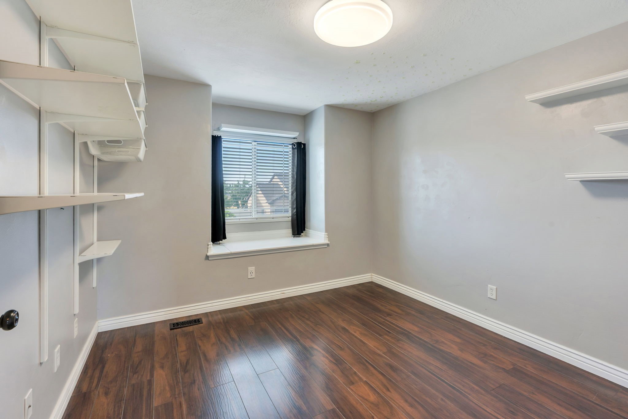 Room featuring wood-finish flooring, light gray walls, and white baseboards