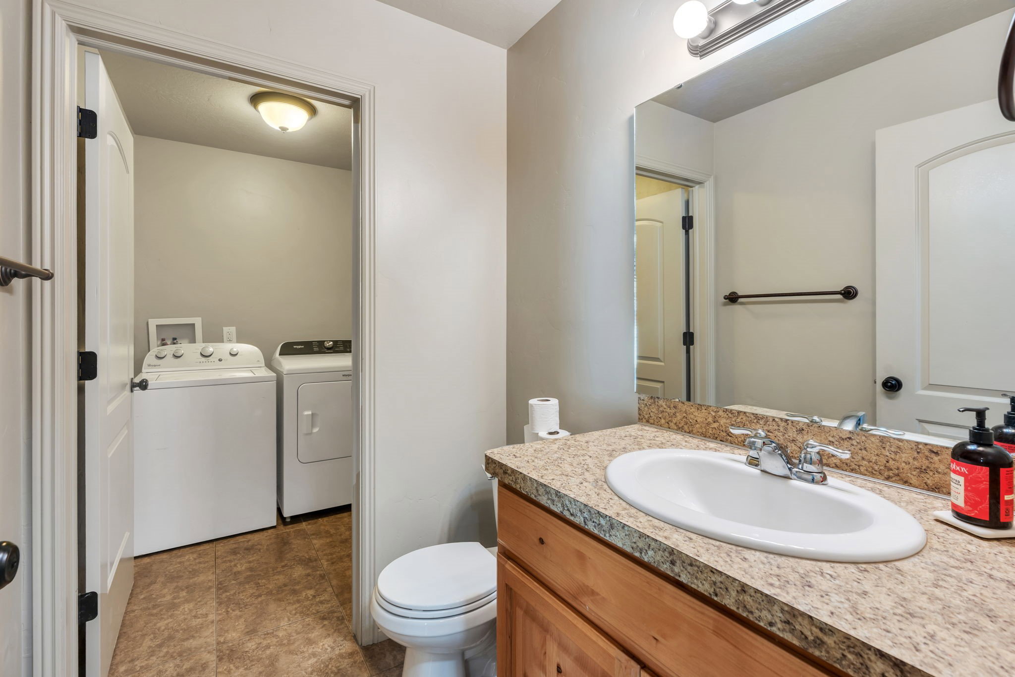 Bathroom vanity with a speckled countertop, undermount sink, and wood-finish cabinetry