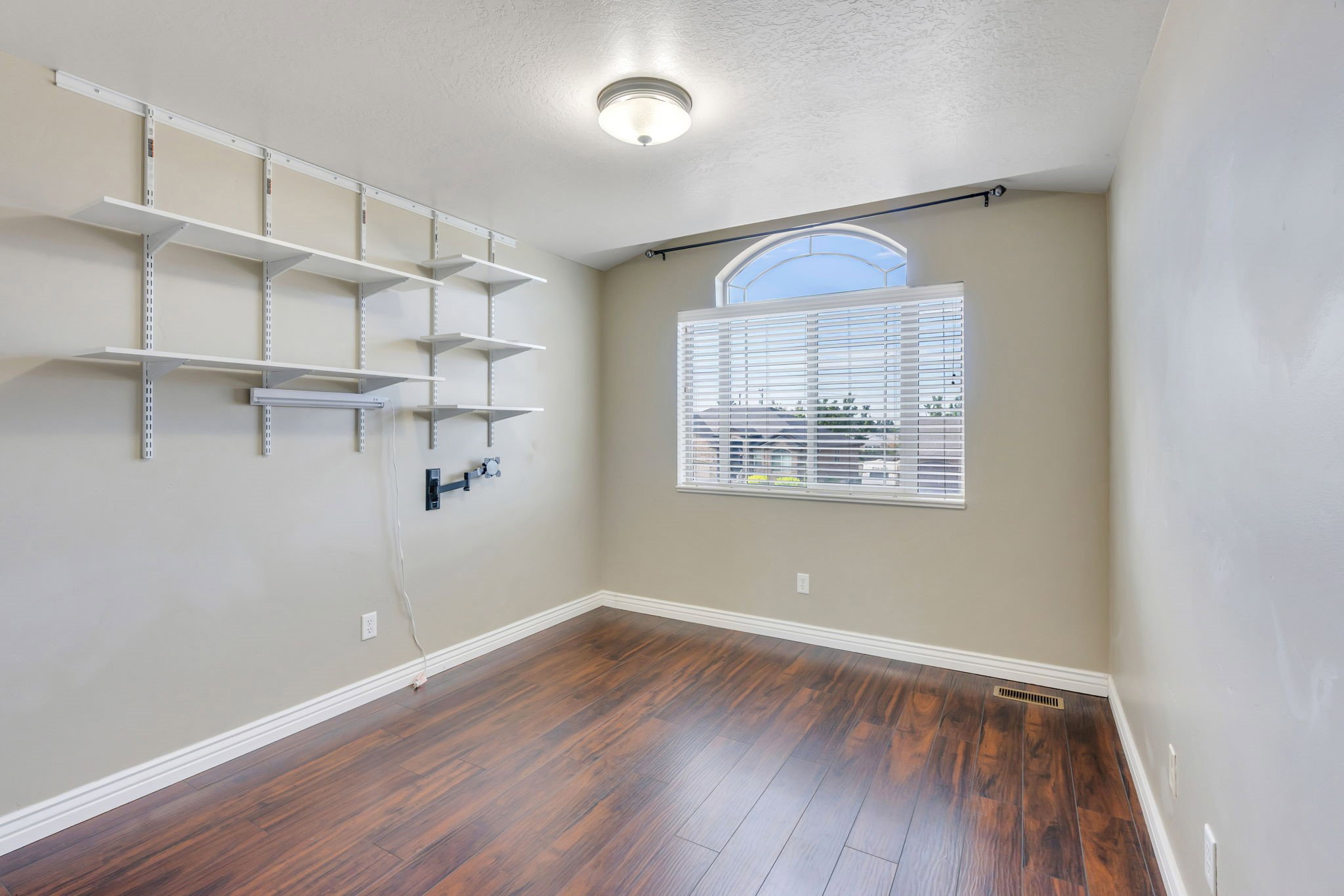 Room featuring wood-finish flooring, a neutral wall color, and white baseboards