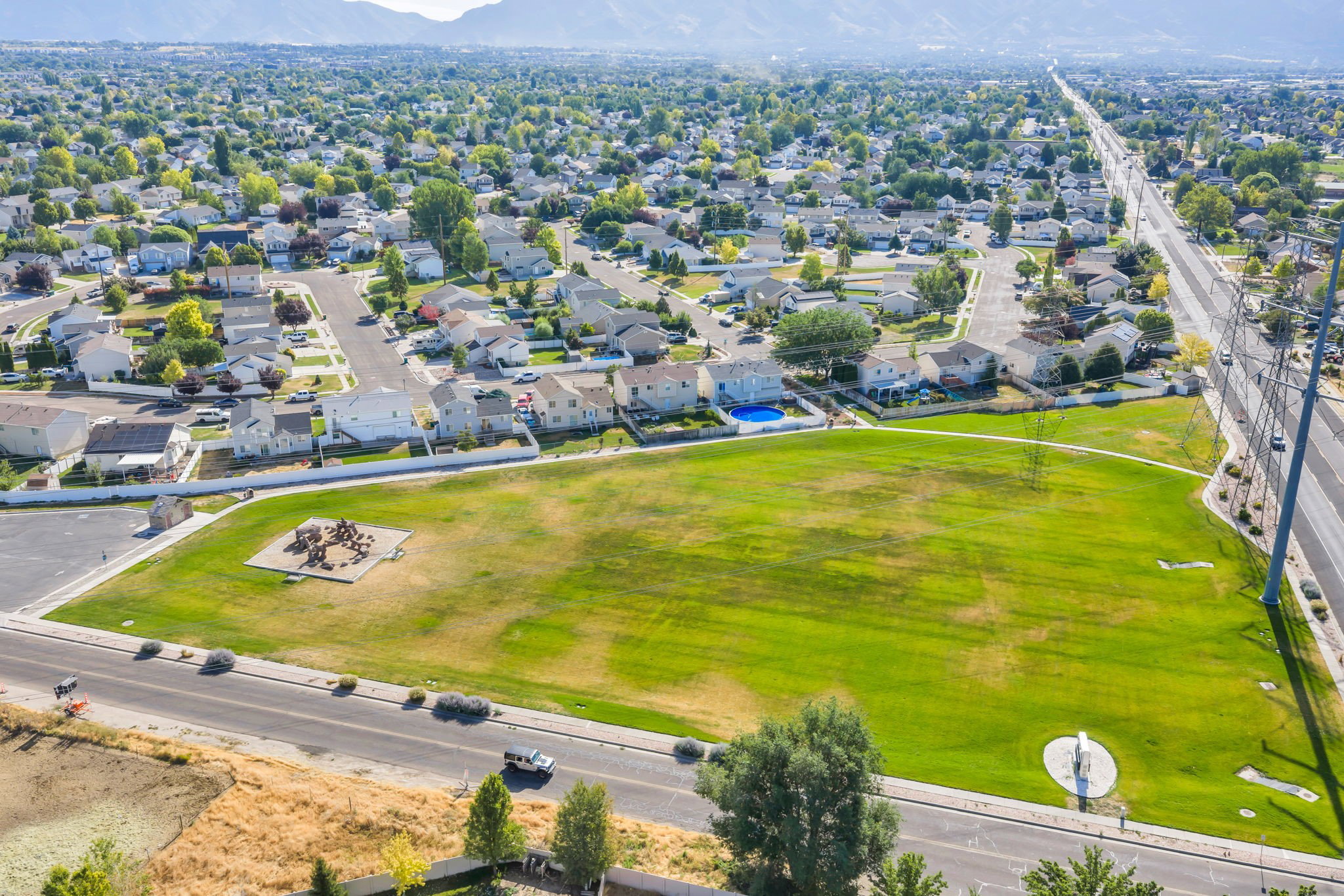 Expansive green space featuring a playground structure and surrounding residential area
