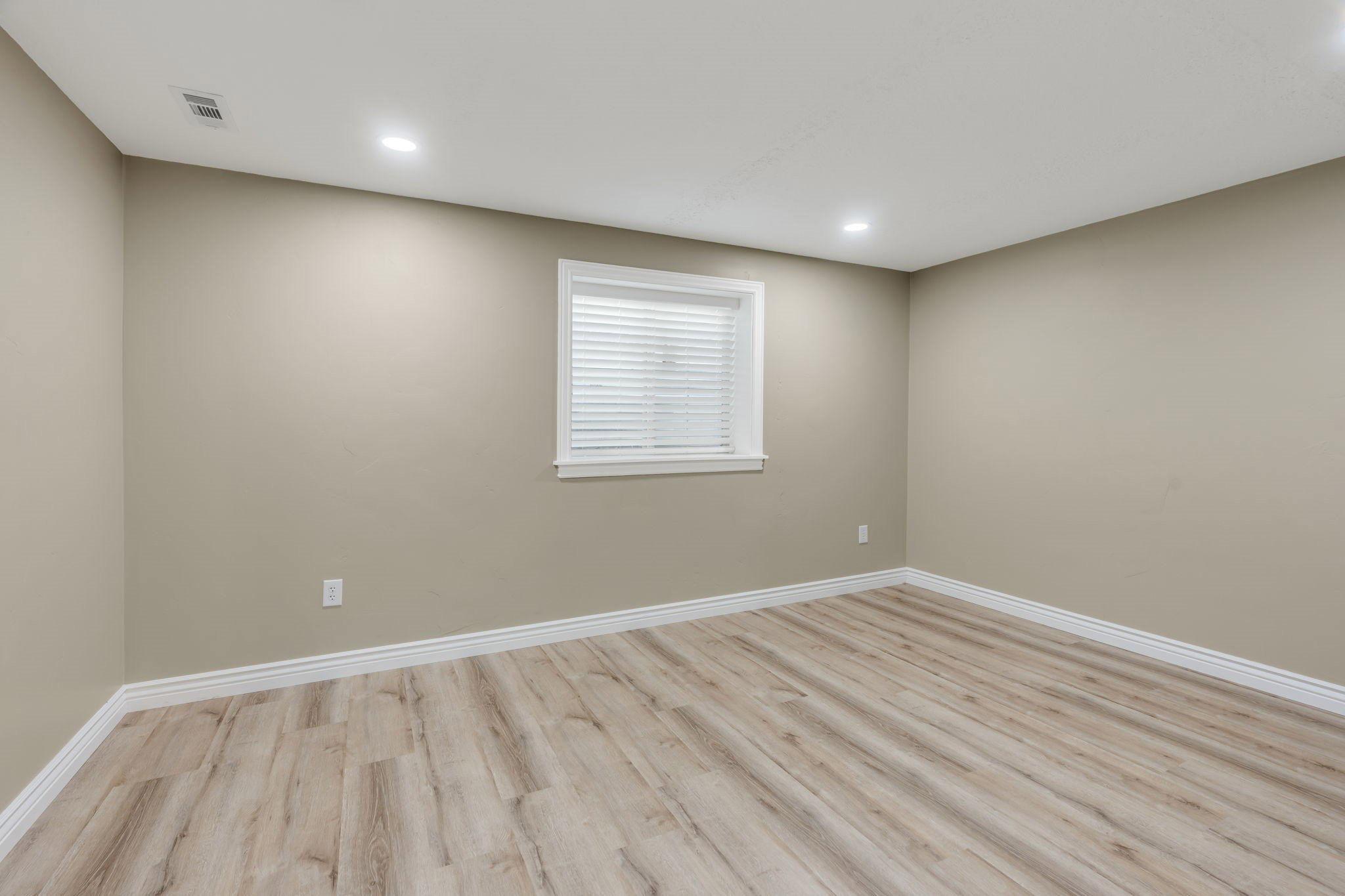 Room with light wood-finish flooring, neutral wall paint, and white baseboards