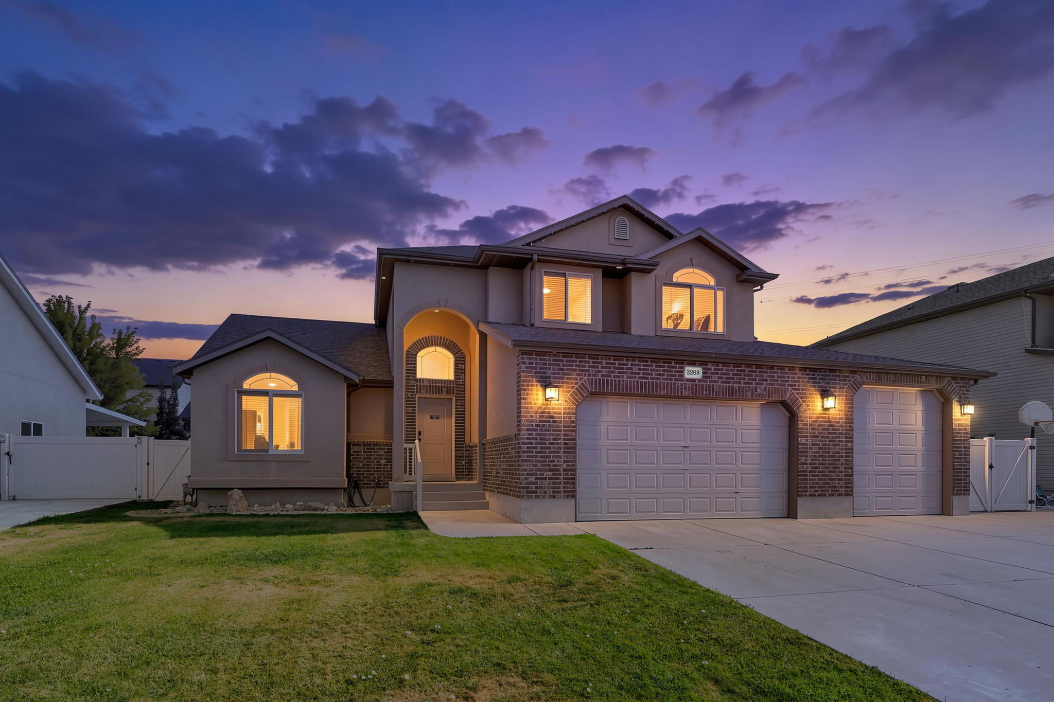 Two-story stucco and brick facade residence featuring a prominent arched entry, three garage bays, and multiple arched windows