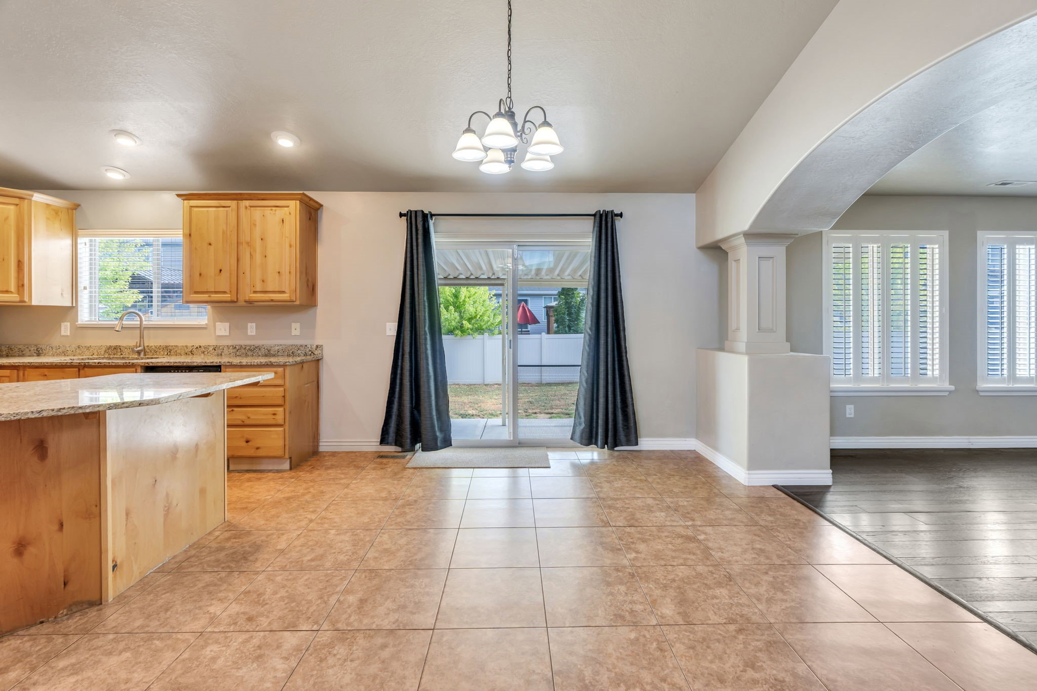 Tiled flooring extends through the dining area with a chandelier, leading to a sliding glass door providing backyard access