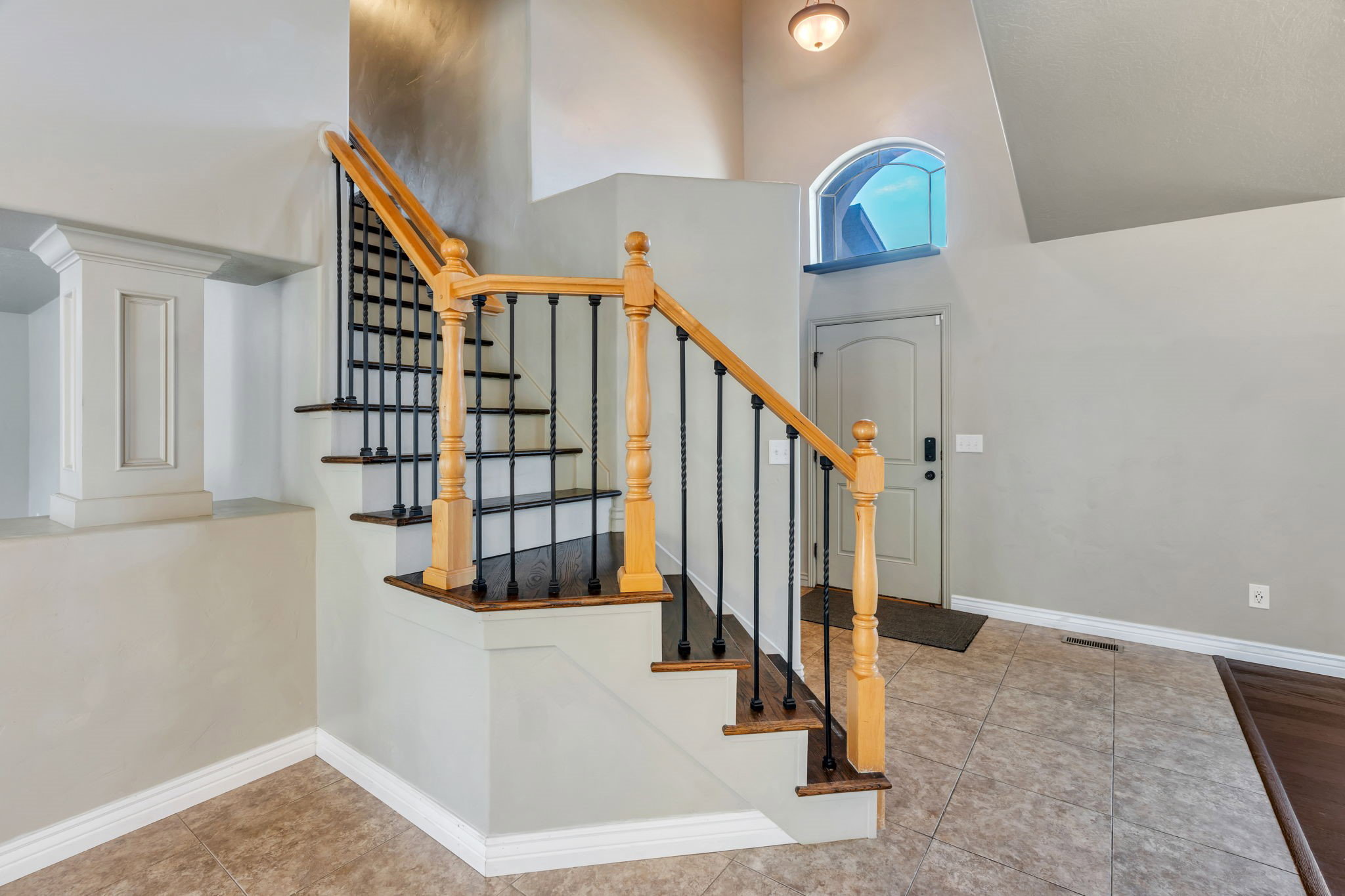 Entryway featuring a staircase with wood newel posts, black wrought iron balusters, and dark wood-finish treads