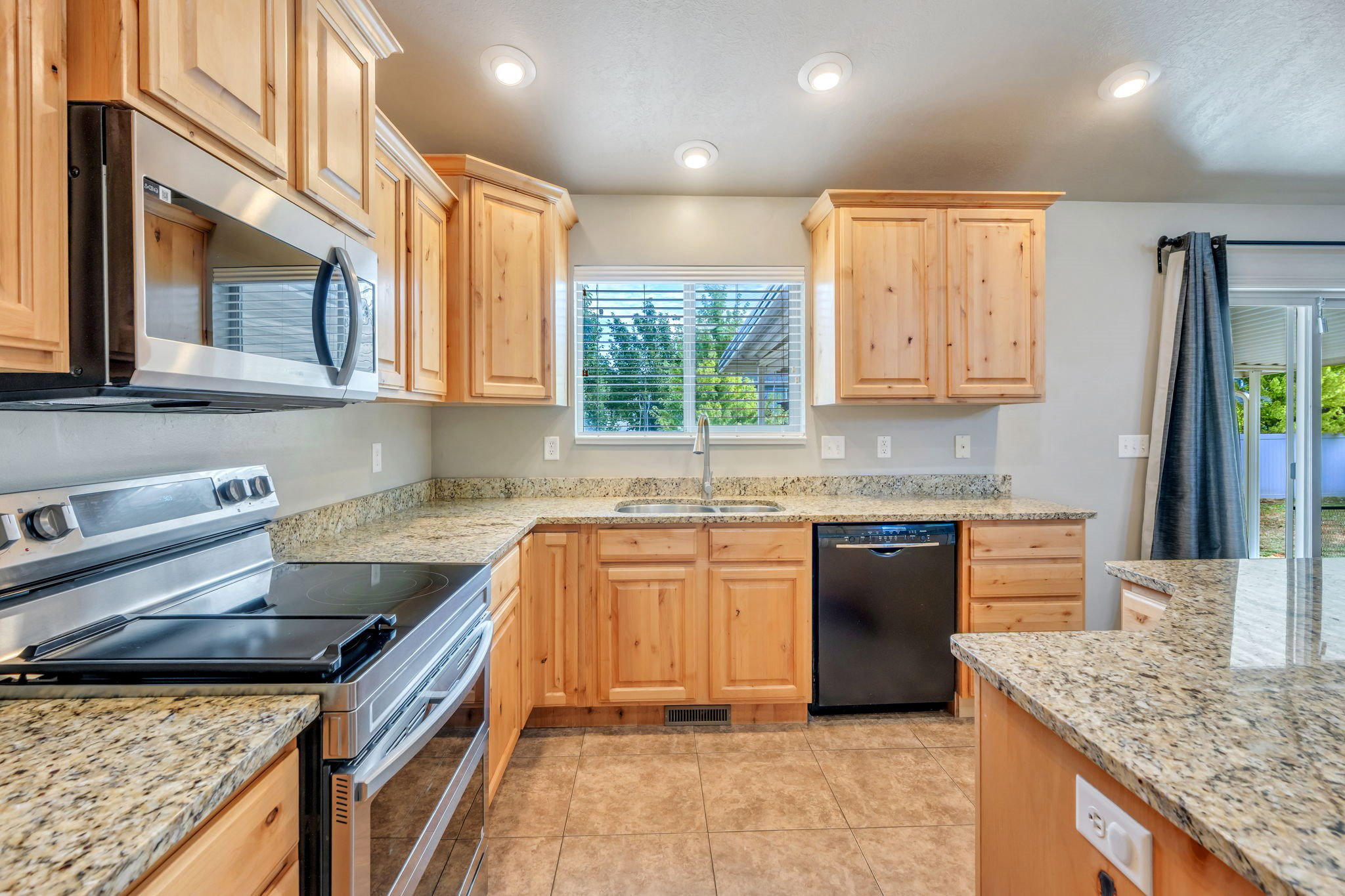 Kitchen featuring wood cabinetry, granite-patterned countertops, and tile flooring