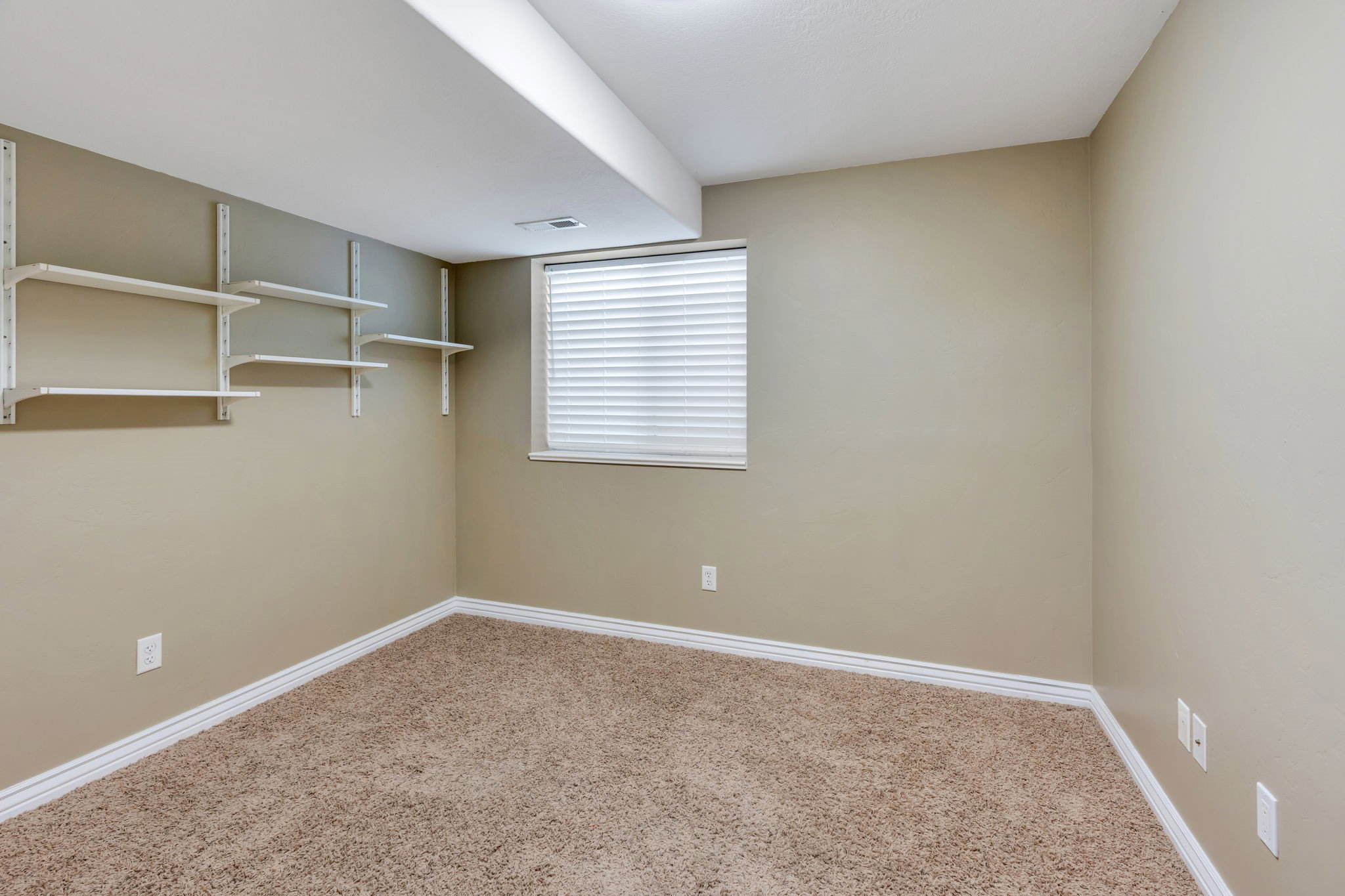 Carpeted room with neutral wall tones and white baseboards