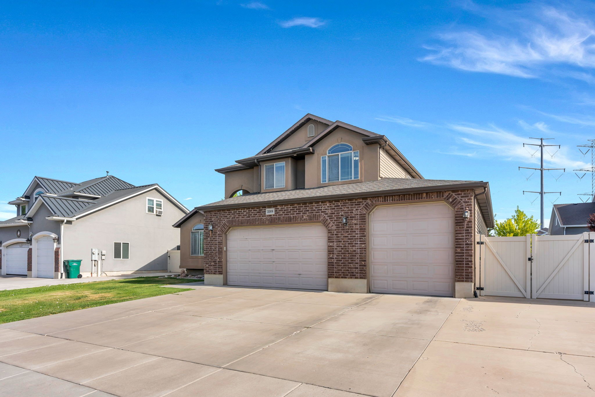 Two-story residence featuring a brick facade with stucco accents and a multi-car garage