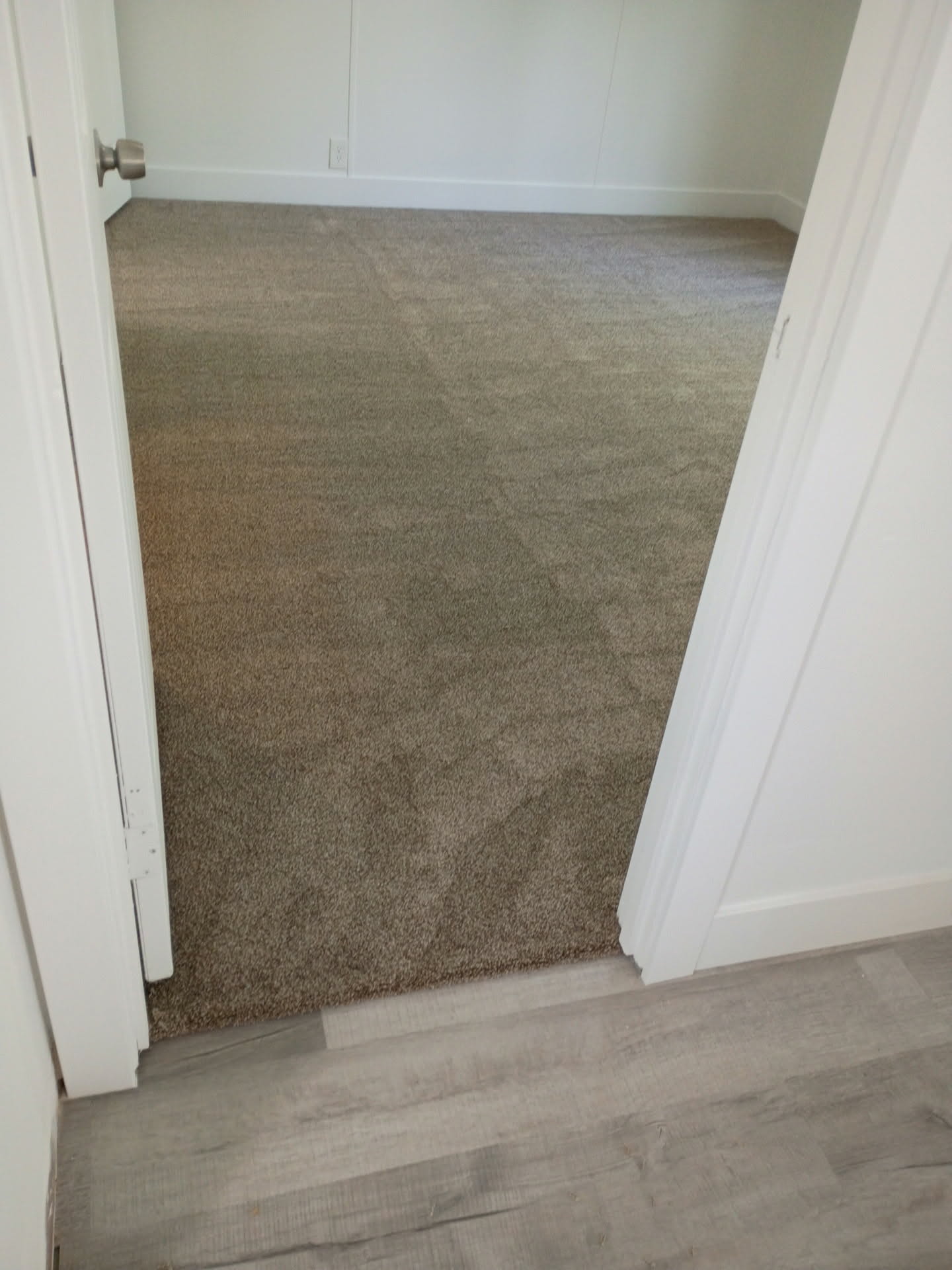 Neutral-toned carpeting extends throughout this room, complemented by white painted walls and baseboards