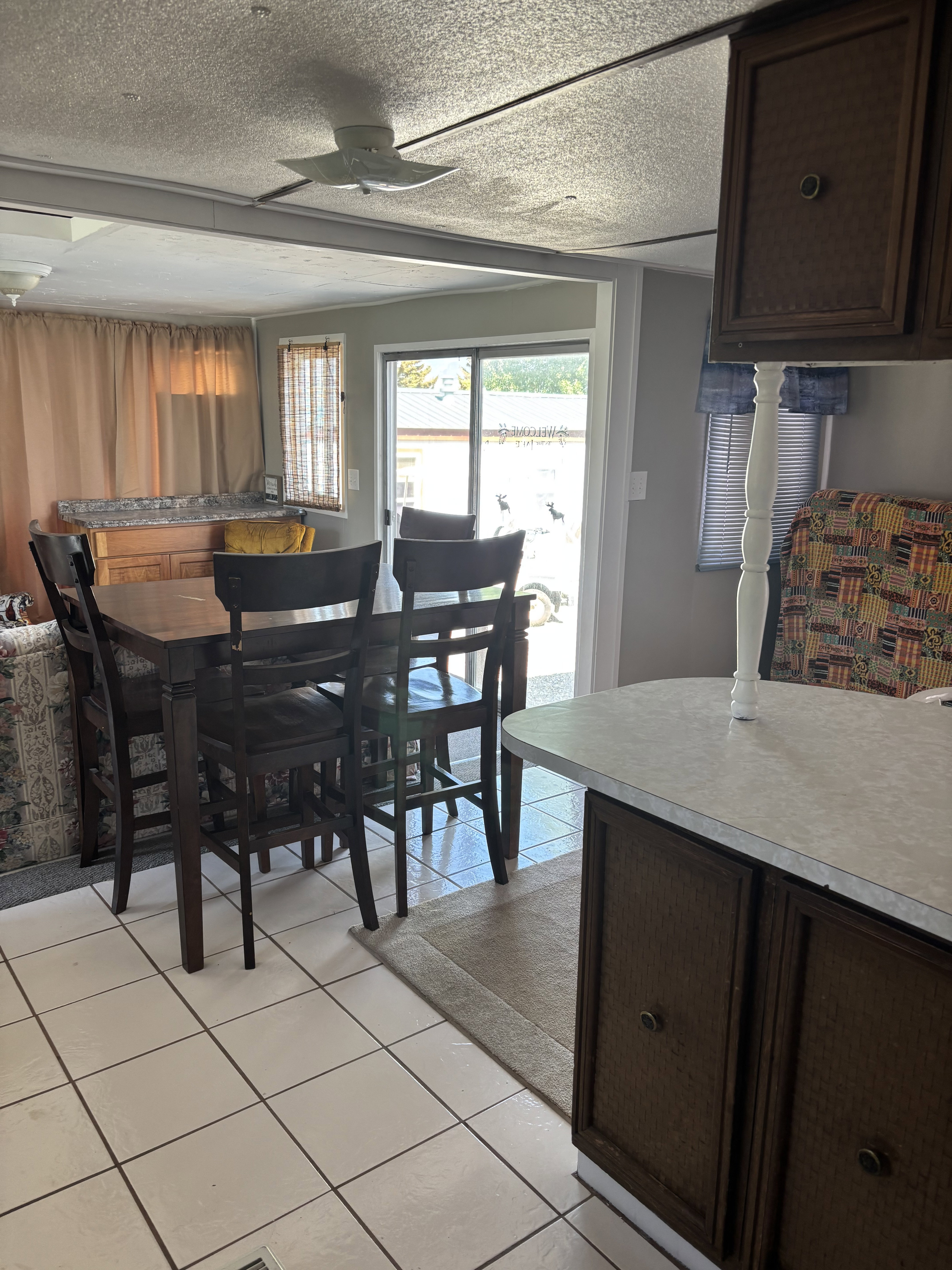 Open concept dining area with white tile flooring and a ceiling fan