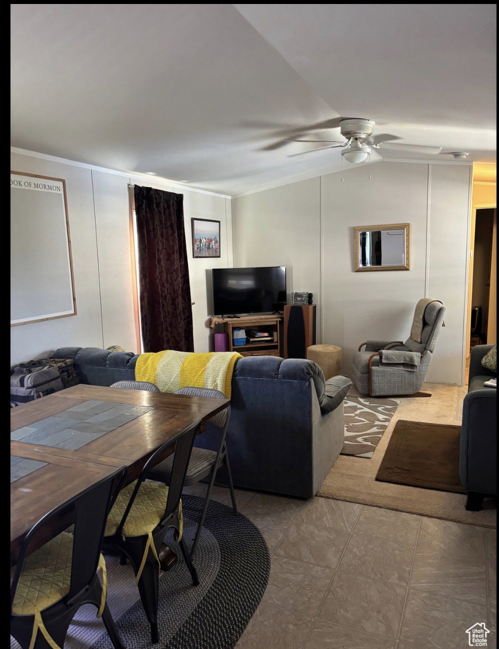 Open-concept living space featuring neutral tone flooring, a ceiling fan with integrated lighting, and vertical wall paneling