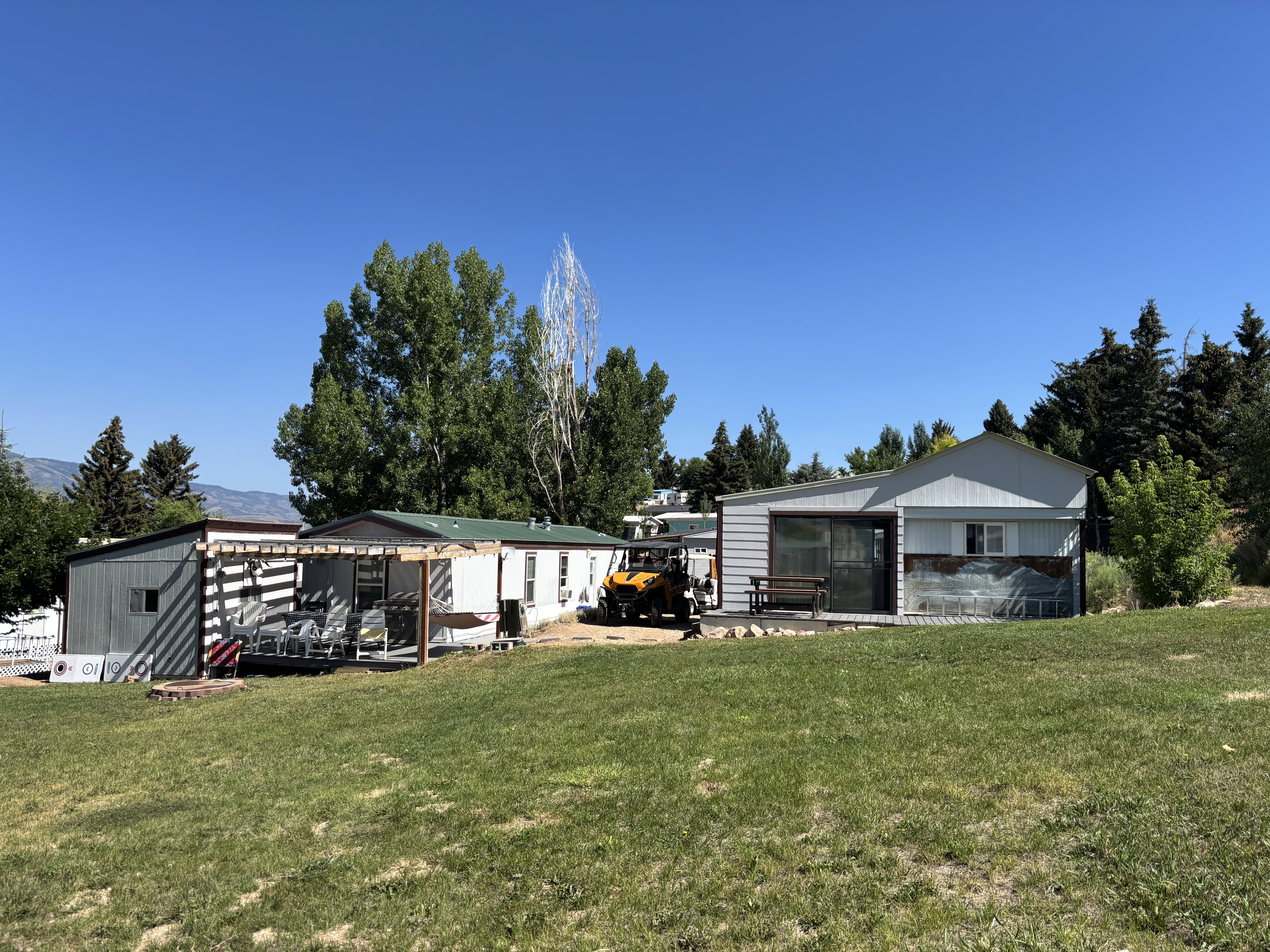 Expansive green lawn featuring two structures with metal siding and pitched roofs