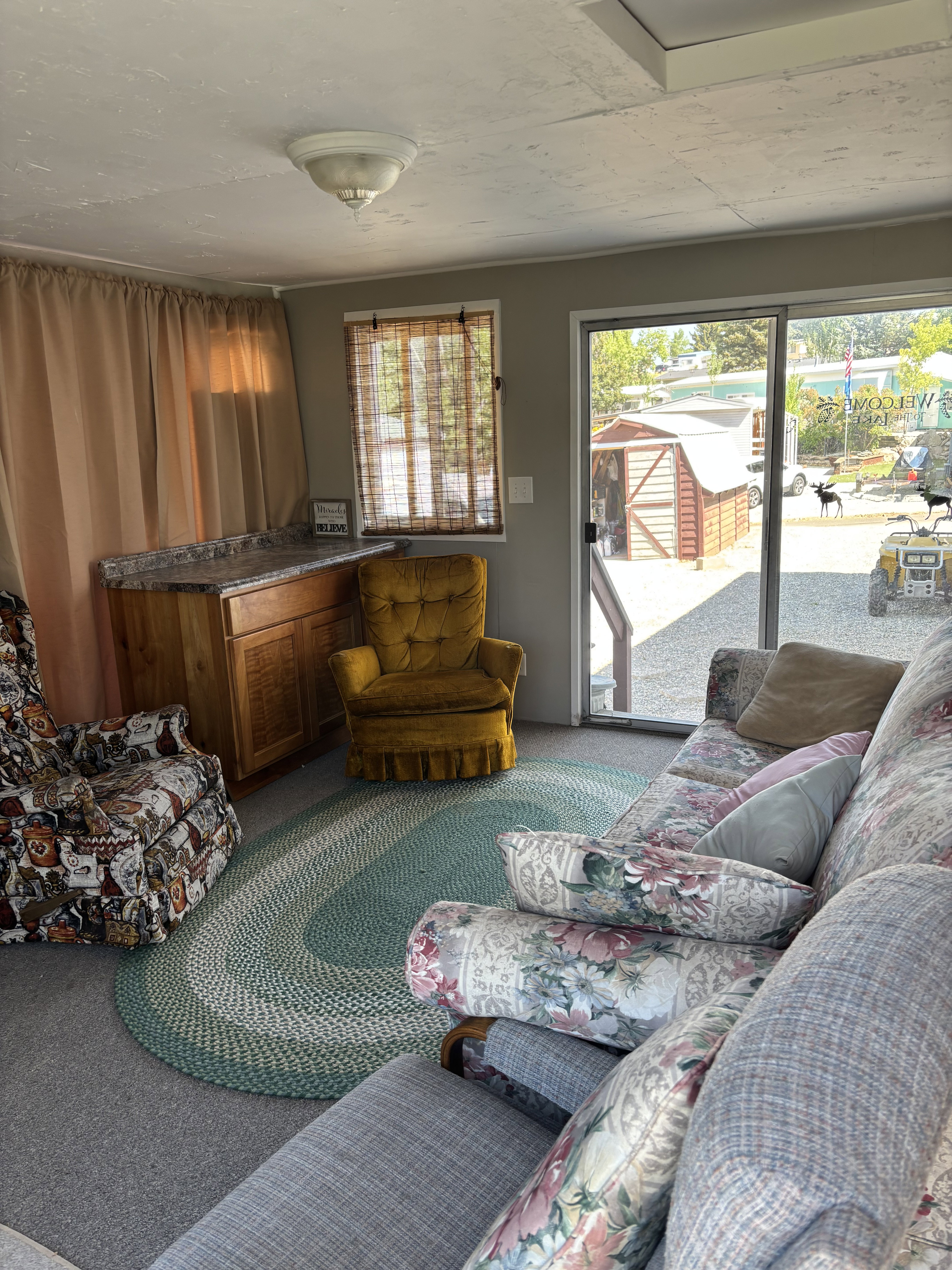 Interior living space featuring light gray walls, carpet flooring, a built-in counter with wood cabinetry, and a sliding glass door providing exterior access