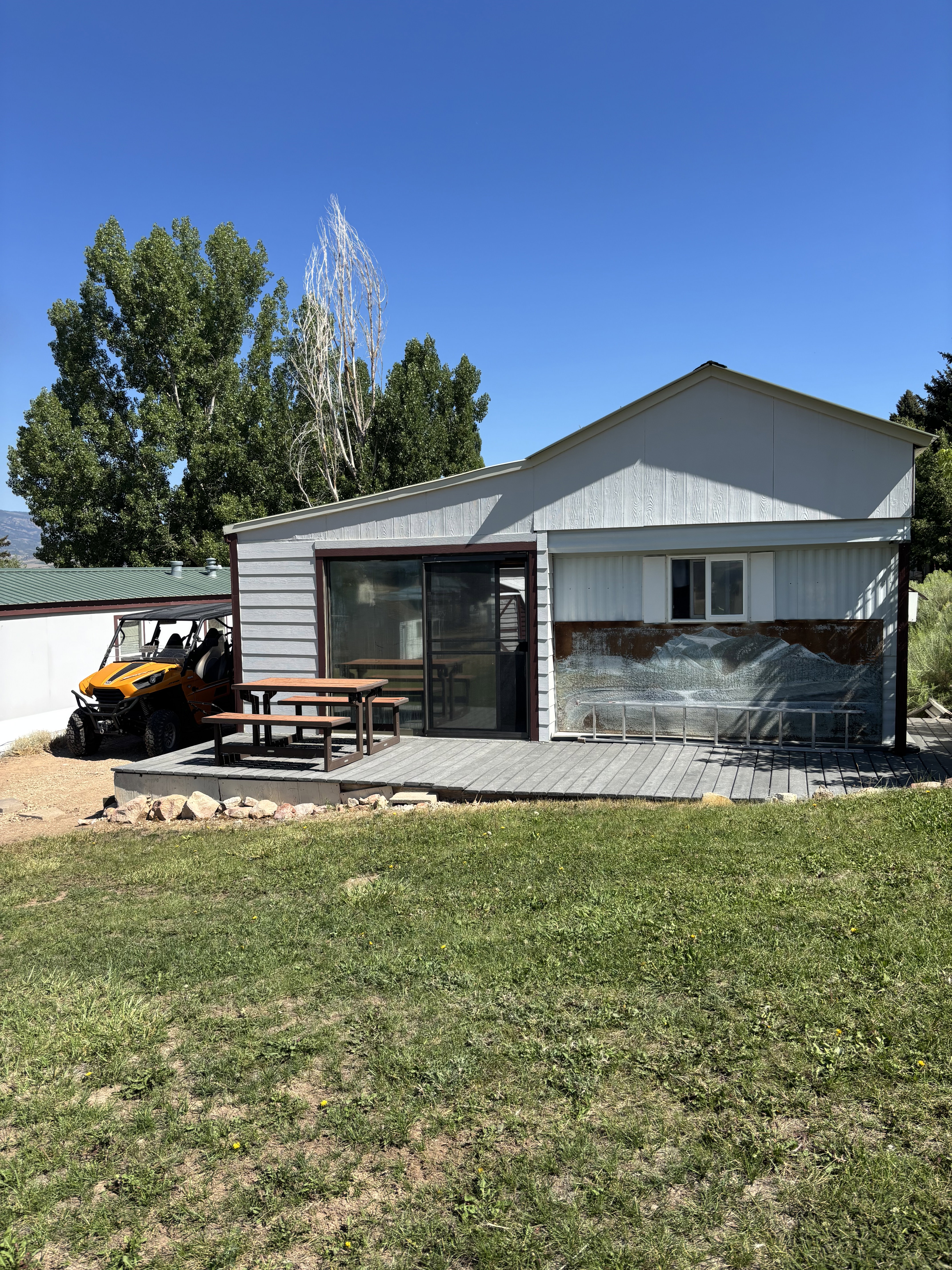 Exterior featuring a raised deck with composite decking, sliding glass door, and white siding