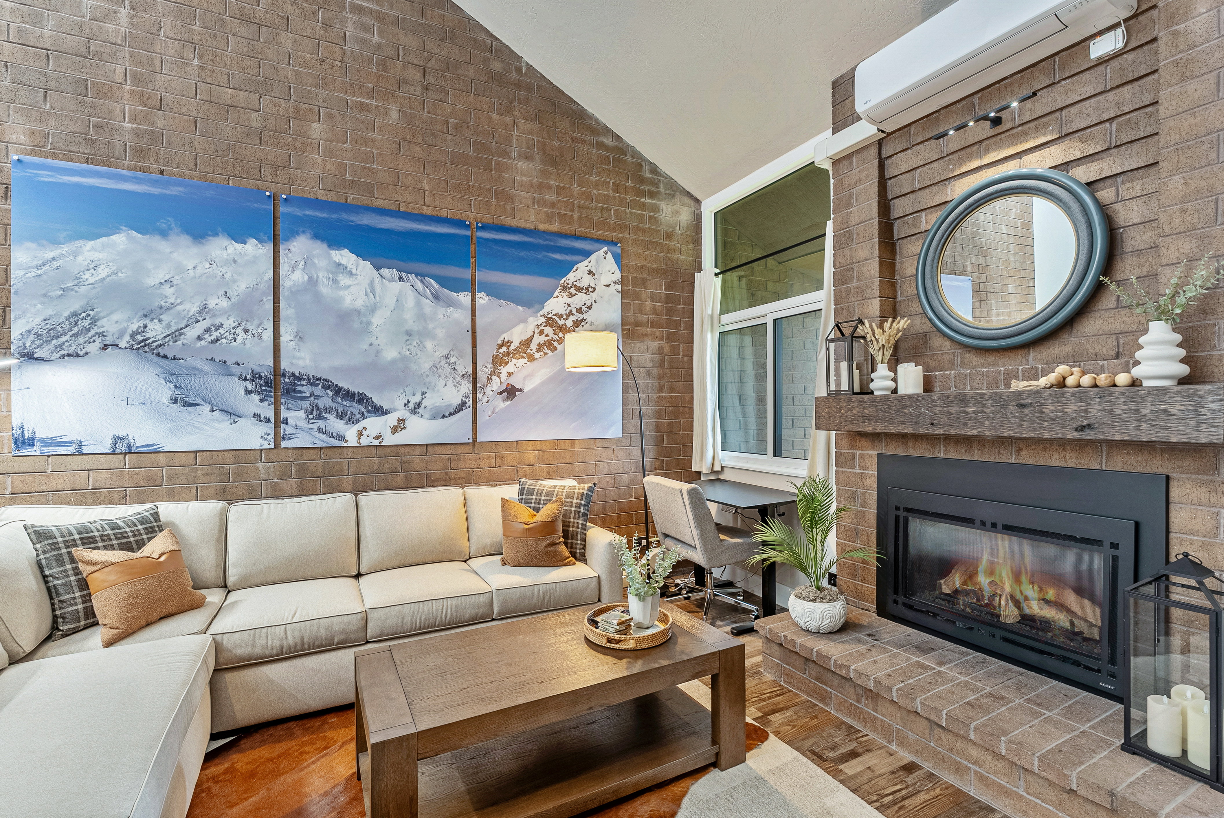 Living area featuring a floor-to-ceiling brick accent wall, vaulted ceiling, and a built-in fireplace with a substantial wood mantel