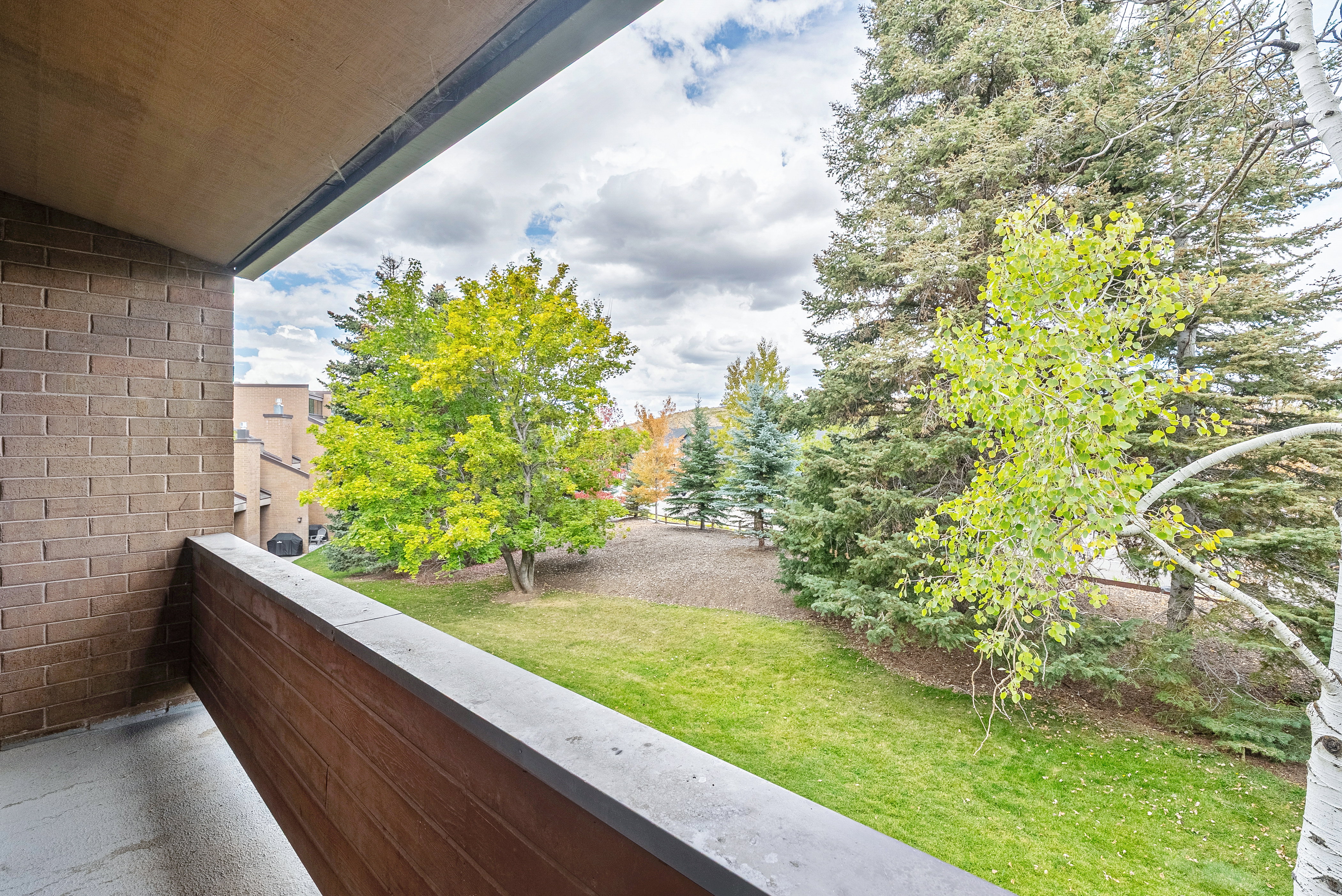 Private balcony featuring a brick-textured wall and a dark, solid railing