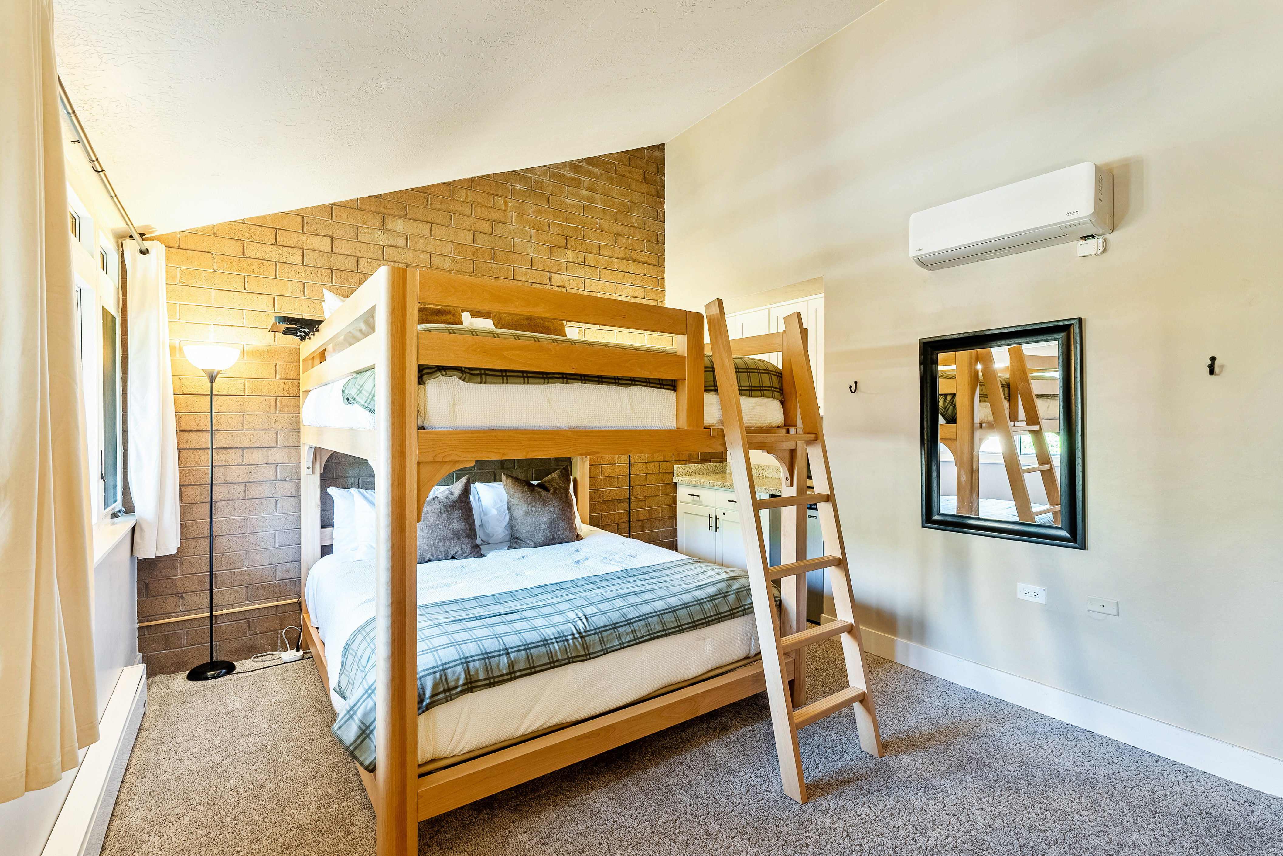 Bedroom featuring a wood bunk bed, brick accent wall, carpet flooring, a wall-mounted mini-split unit, and a built-in cabinet with a countertop