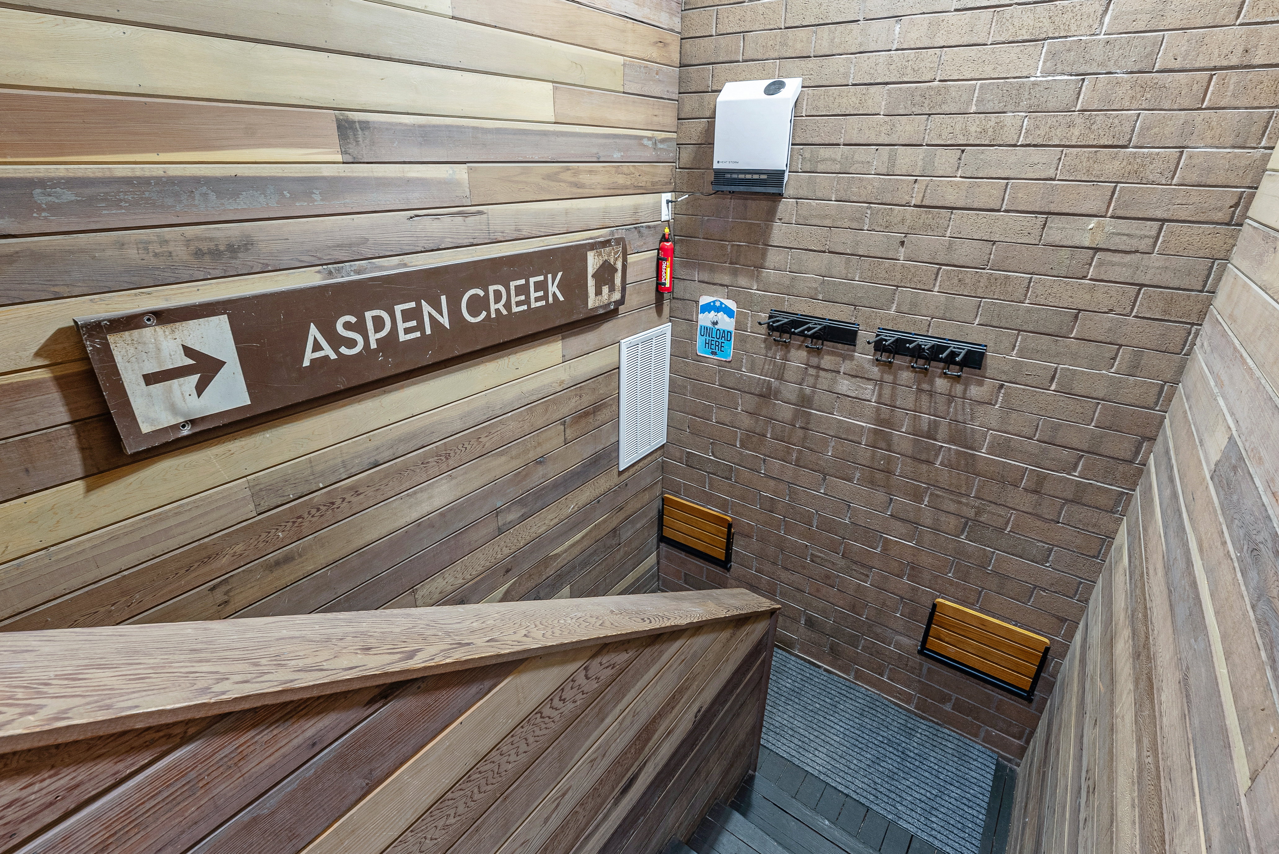 Stairwell featuring wood-finish wall paneling, brick-finish wall, and integrated wooden handrail