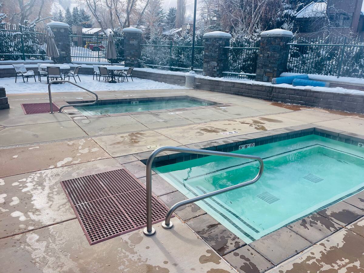Outdoor aquatic area featuring two separate in-ground spas with handrails and integrated steps