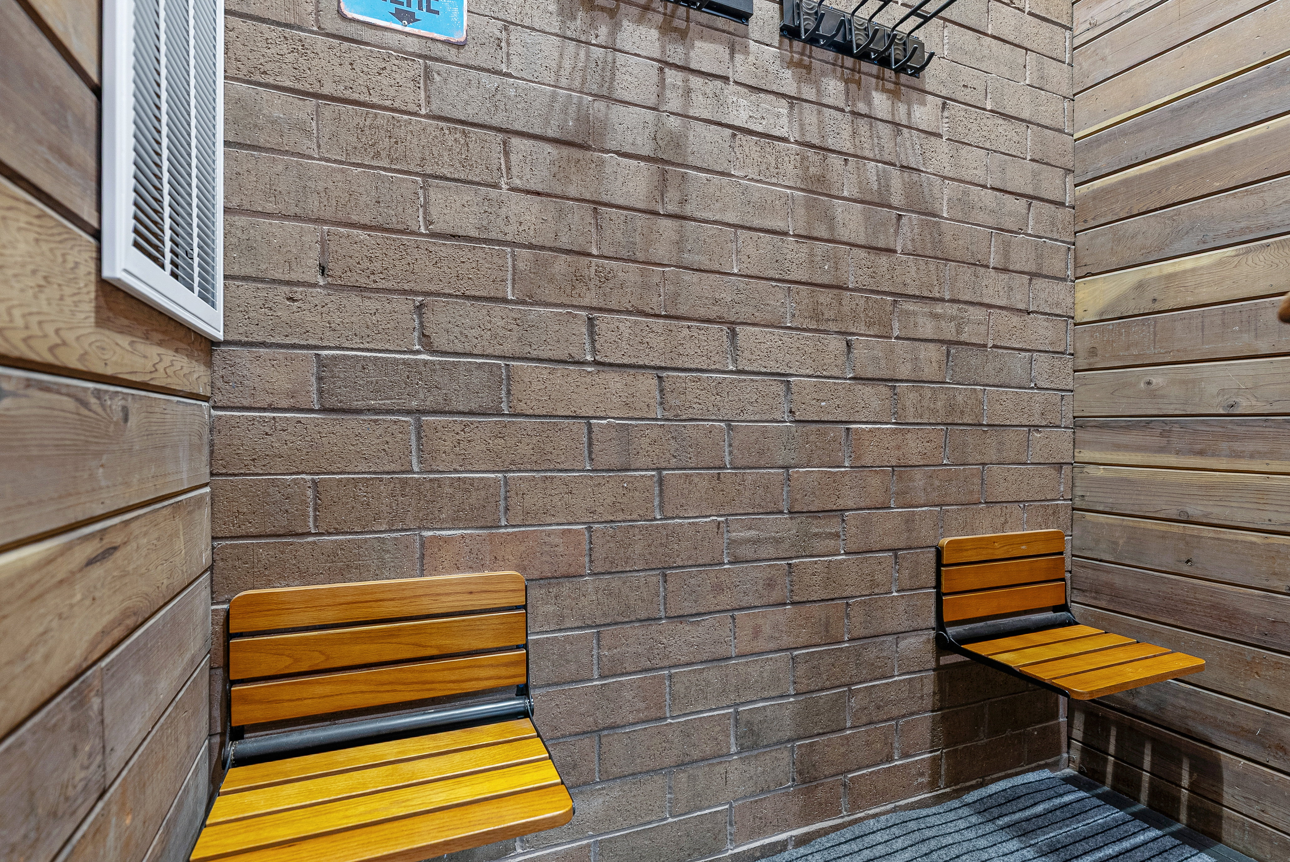 Textured brick wall with two integrated wood-slat folding benches