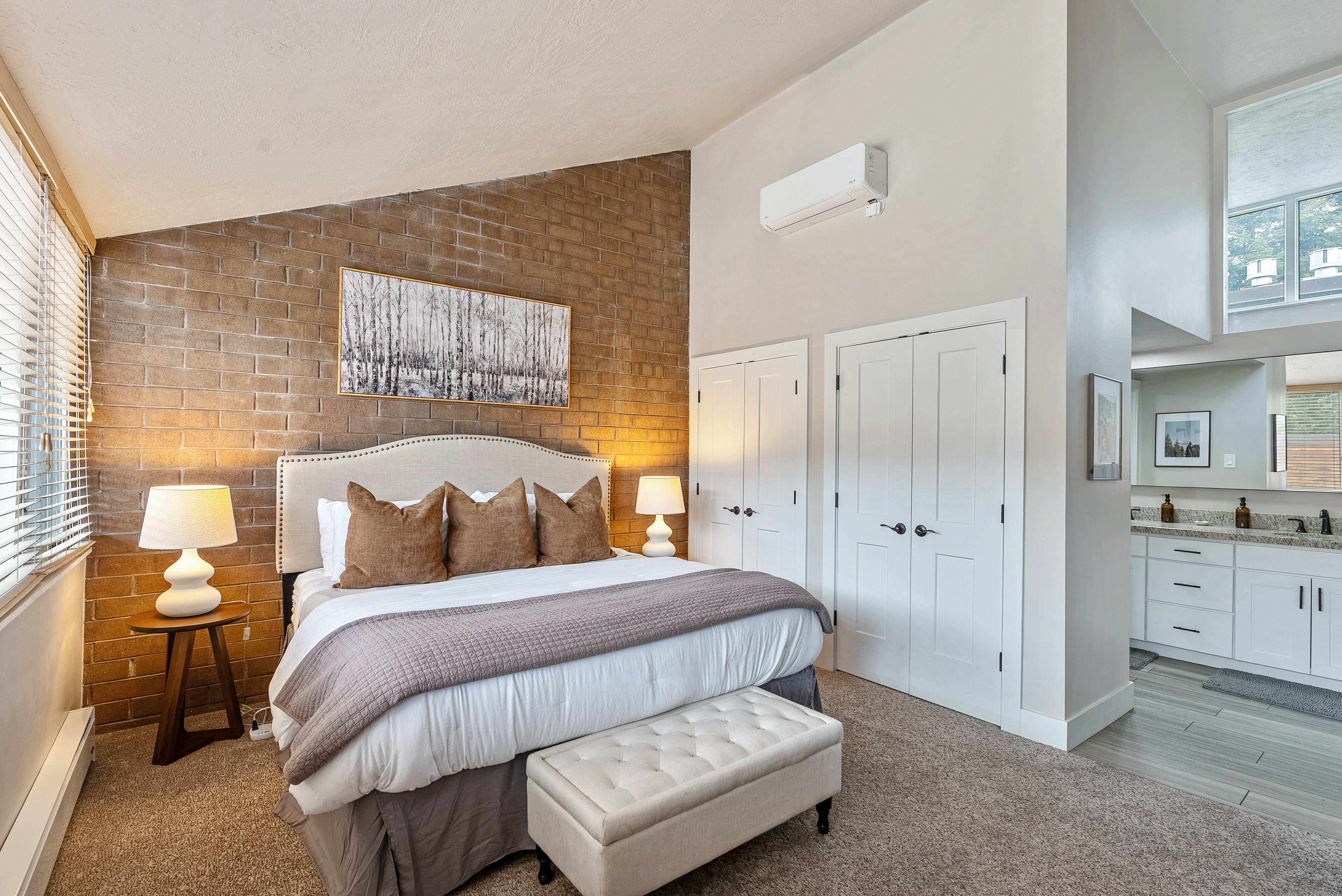 Bedroom area featuring a textured brick accent wall and light-colored carpeting