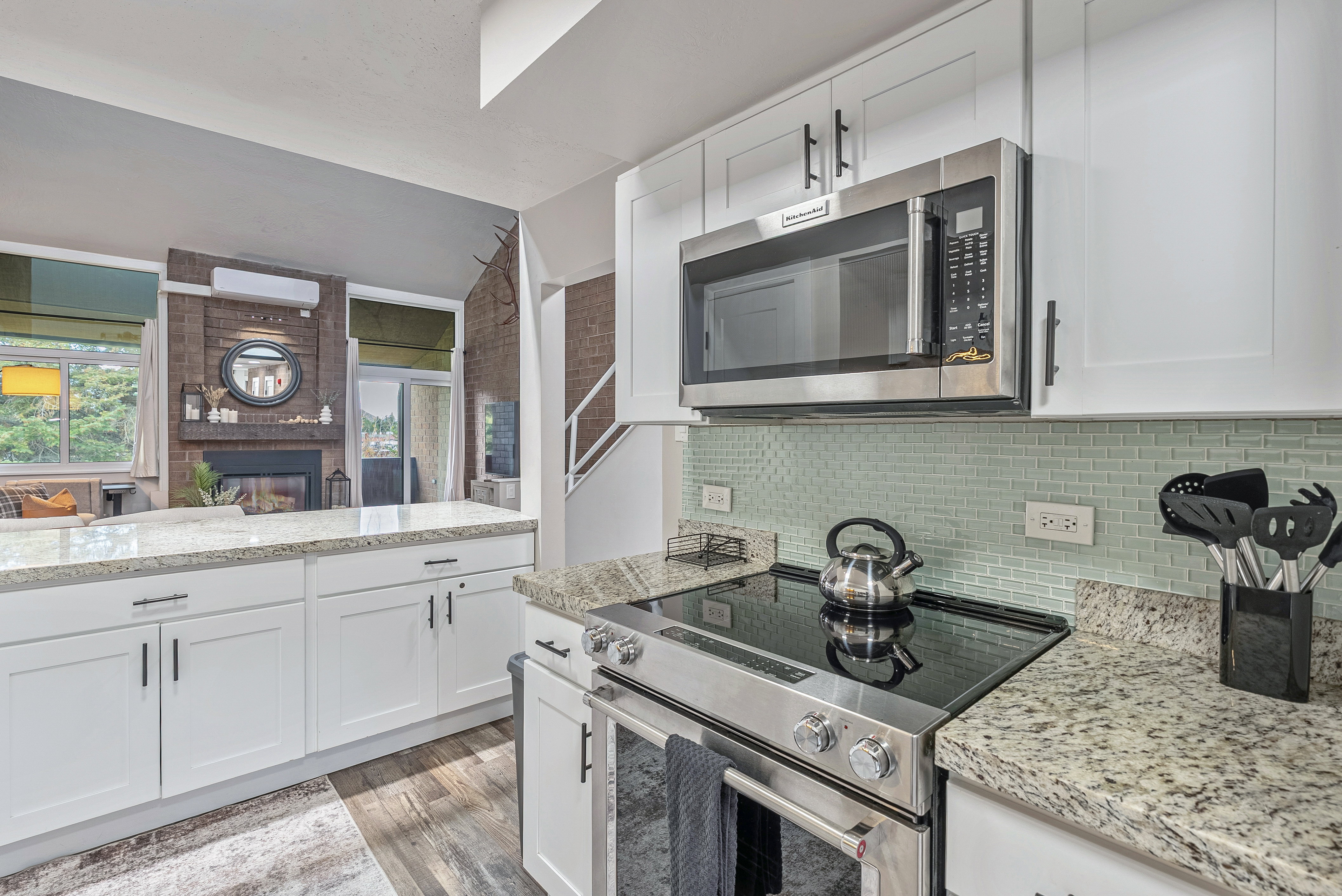 Modern kitchen featuring white cabinetry with dark hardware, granite countertops, and a subway tile backsplash