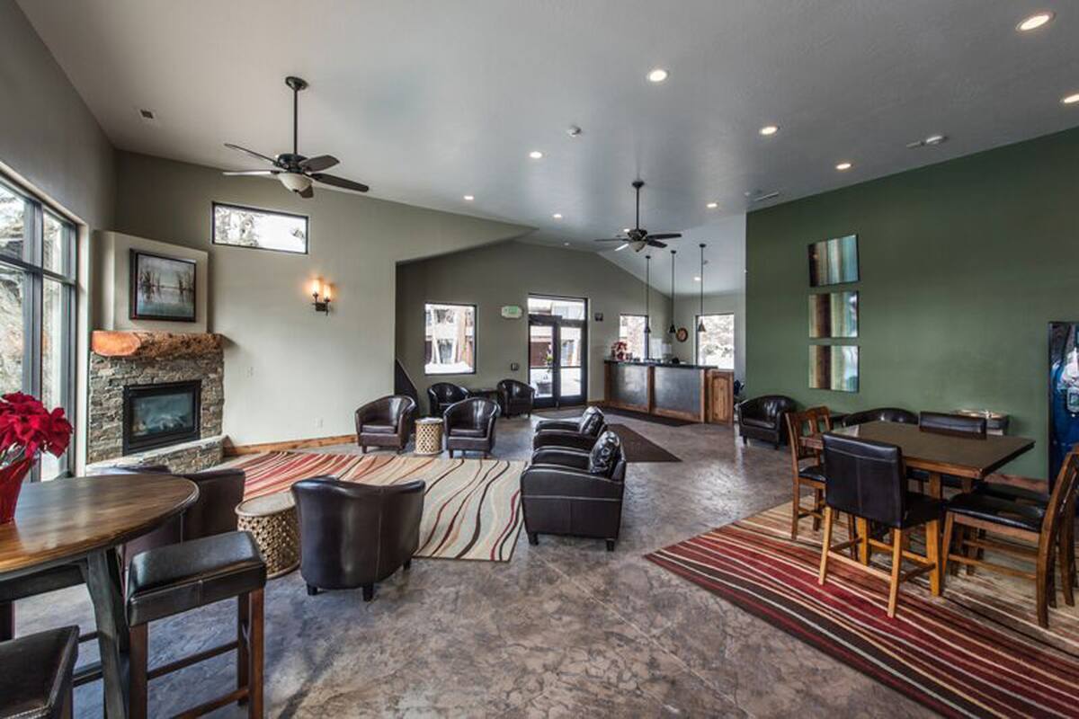 Spacious common area featuring a stone-clad fireplace with a wood mantel, vaulted ceilings, and recessed lighting