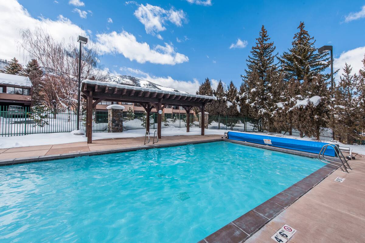 Outdoor swimming pool featuring a pergola, concrete decking, and metal fencing