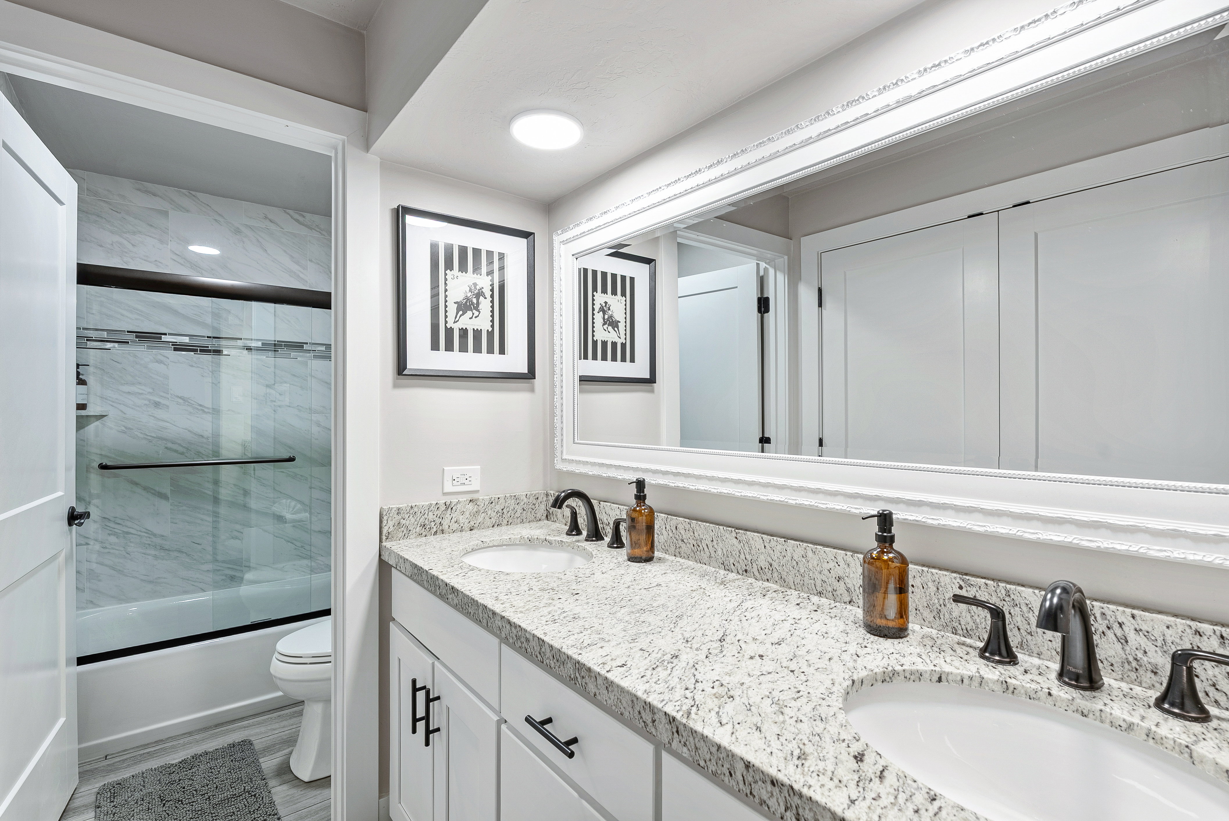 Bathroom featuring a double vanity with stone countertops, undermount sinks, and matte black hardware