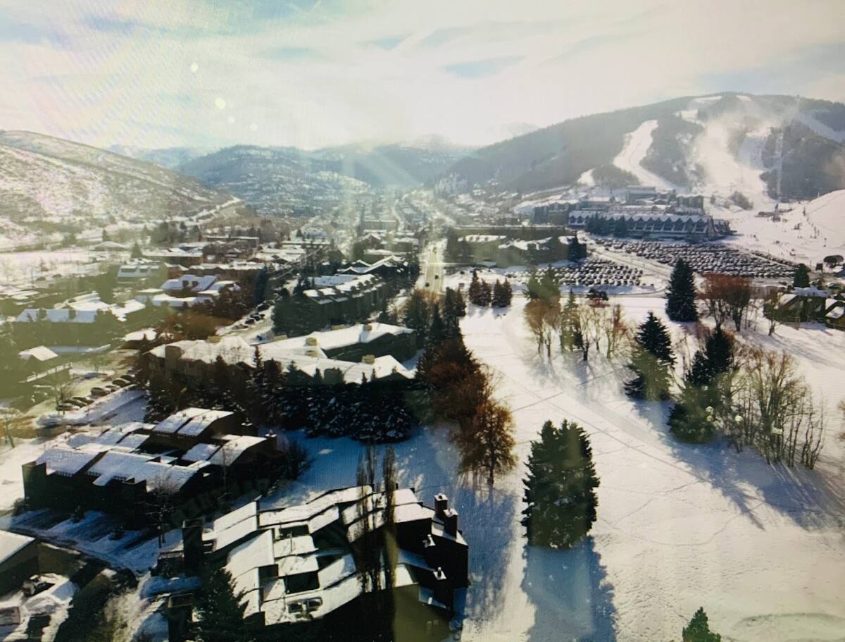 Snow-covered mountainous terrain featuring ski slopes, a town center, and surrounding properties with snow-dusted roofs