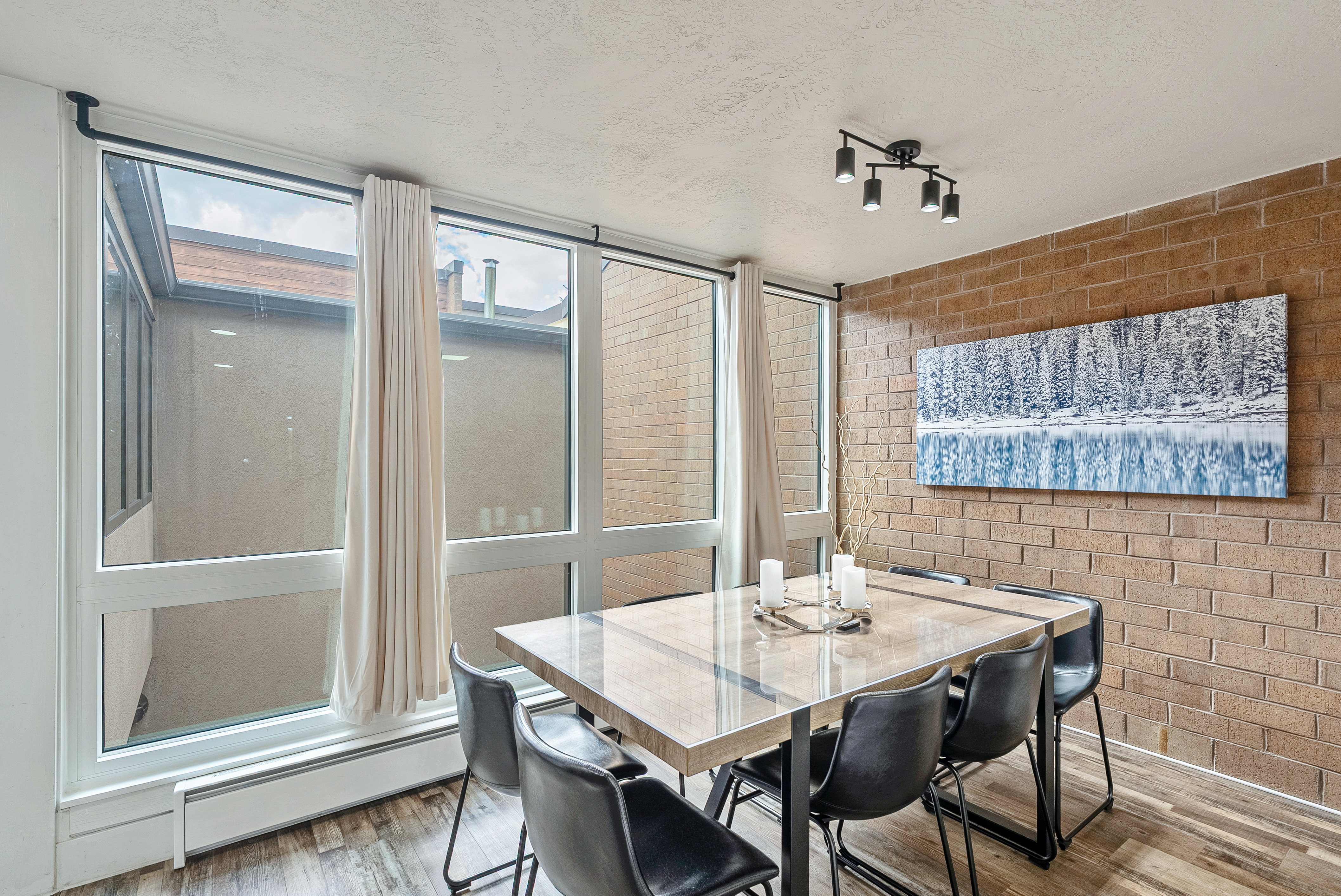 Dining area featuring an exposed brick accent wall and large windows