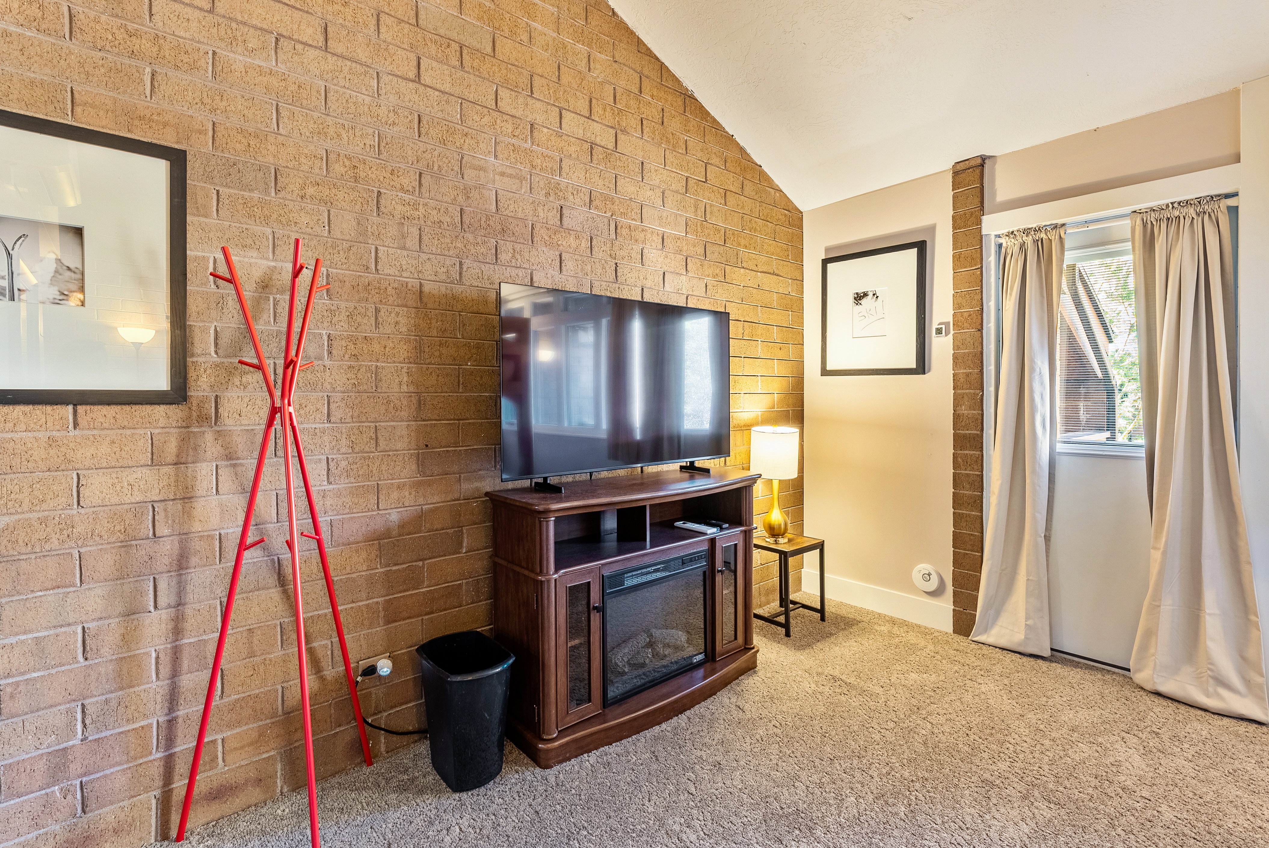 Exposed brick wall with vaulted ceiling and plush carpet flooring