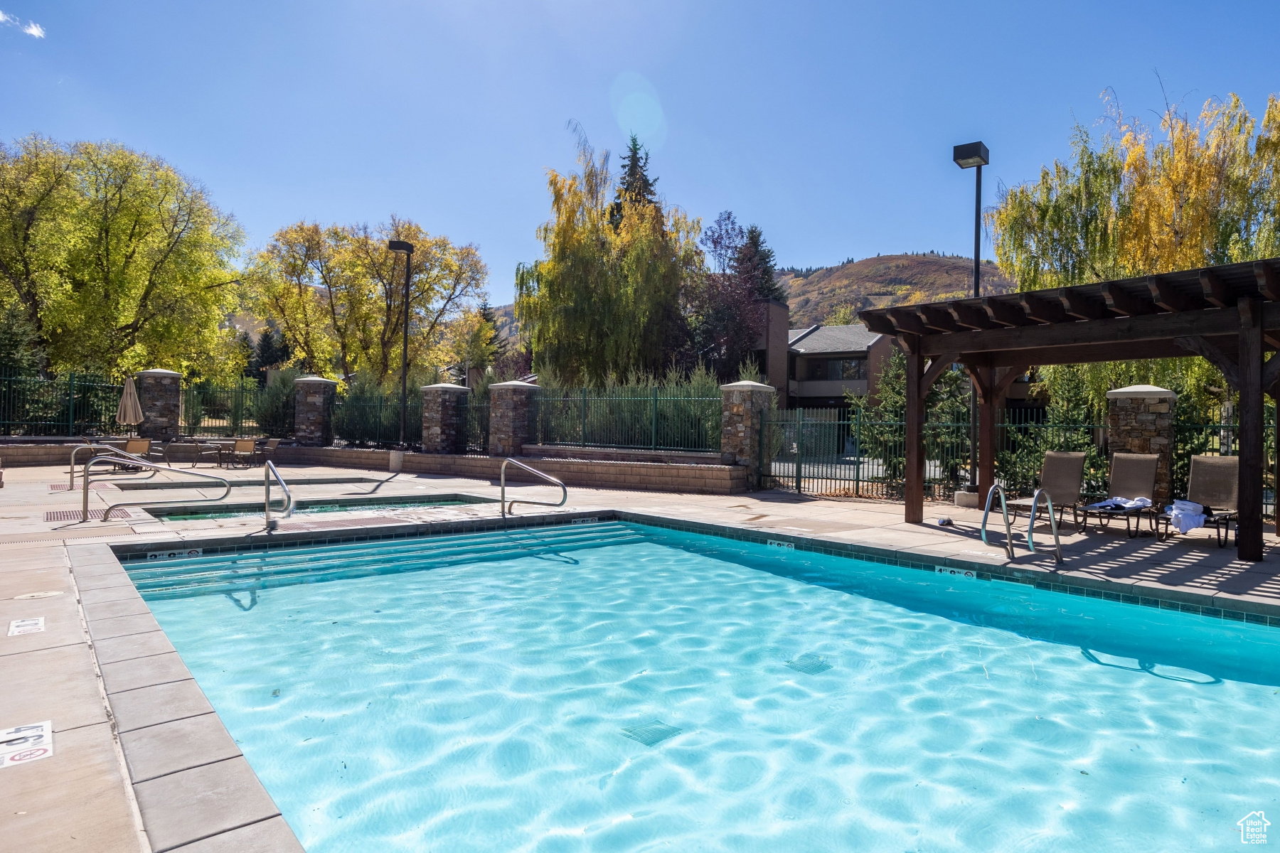 Outdoor swimming pool with integrated spa and surrounding stone-clad pillars