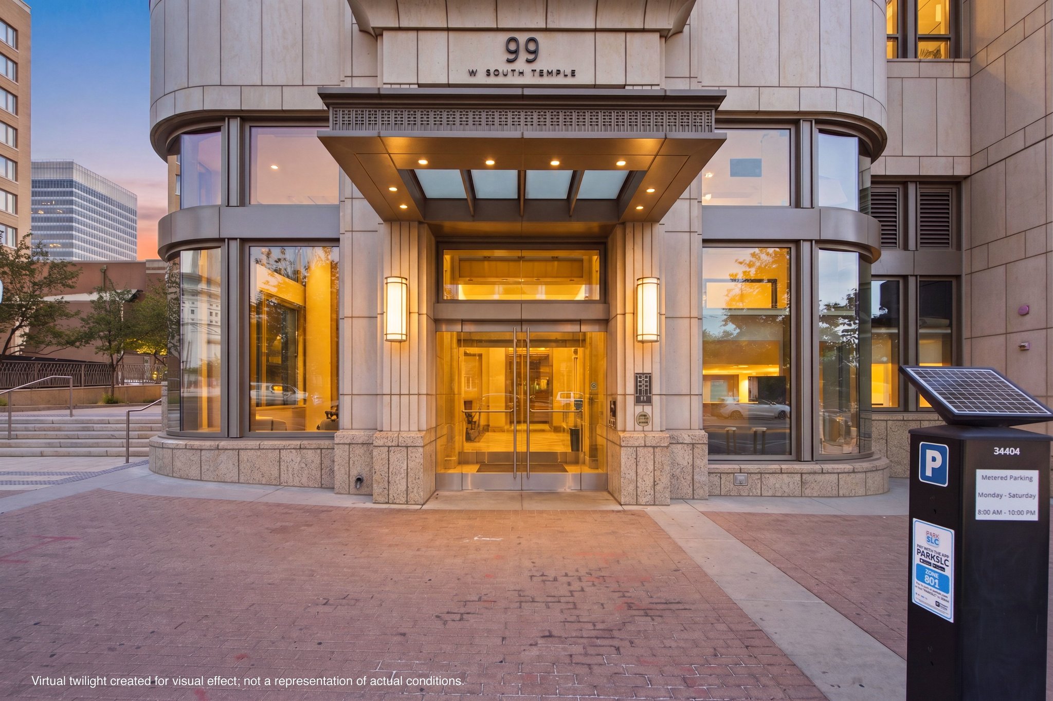 Modern building entrance featuring a glass canopy, double glass doors, and stone facade