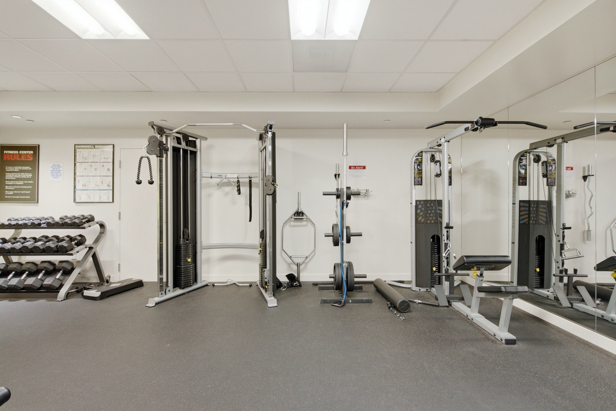 Dedicated fitness center featuring weight training equipment, mirrored walls, and resilient flooring